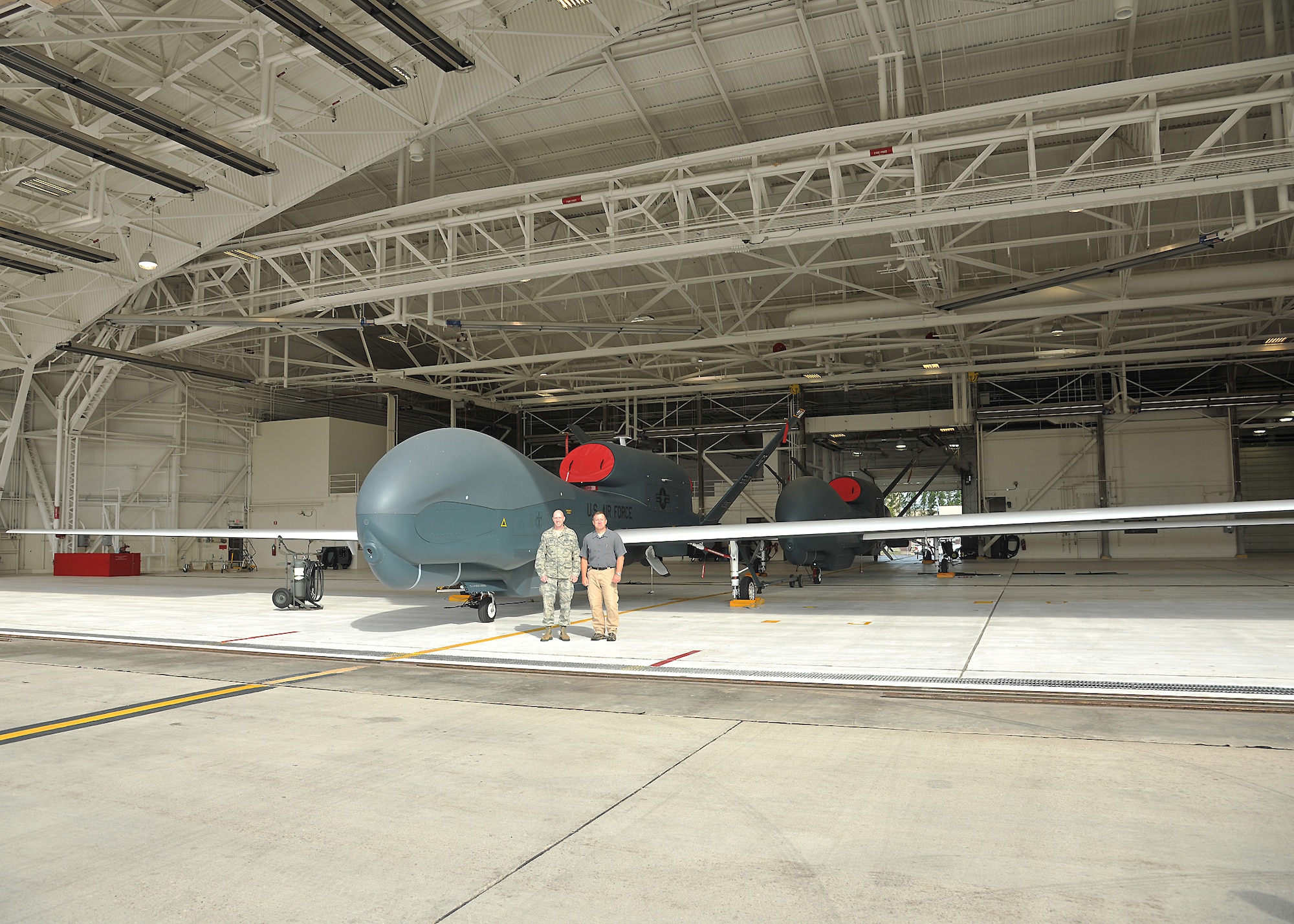 Chief Master Sgt. Wayne Reynolds, air traffic manager and Brendan Smith, anti-terrorism officer, from Volk Field Air National Guard Base, Wis., stand in front of the RQ-4 Block 40 Global Hawk, Sept. 19, 2013, on Grand Forks Air Force Base, N.D. The purpose of their visit was to assist the Air National Guard at Volk Field in building their Unmanned Aircraft Systems program, while also strengthening the possibility of using their airfield in the future in case of any emergency or weather diverts. (U.S. Air Force photo/Senior Airman Xavier Navarro)