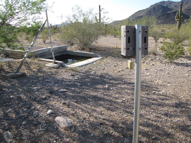 A motion-activated camera stands ready to capture images of wildlife visiting an artificial water site at the Barry M. Goldwater Range-East in southwestern Arizona.   Photo: A. Alvidrez