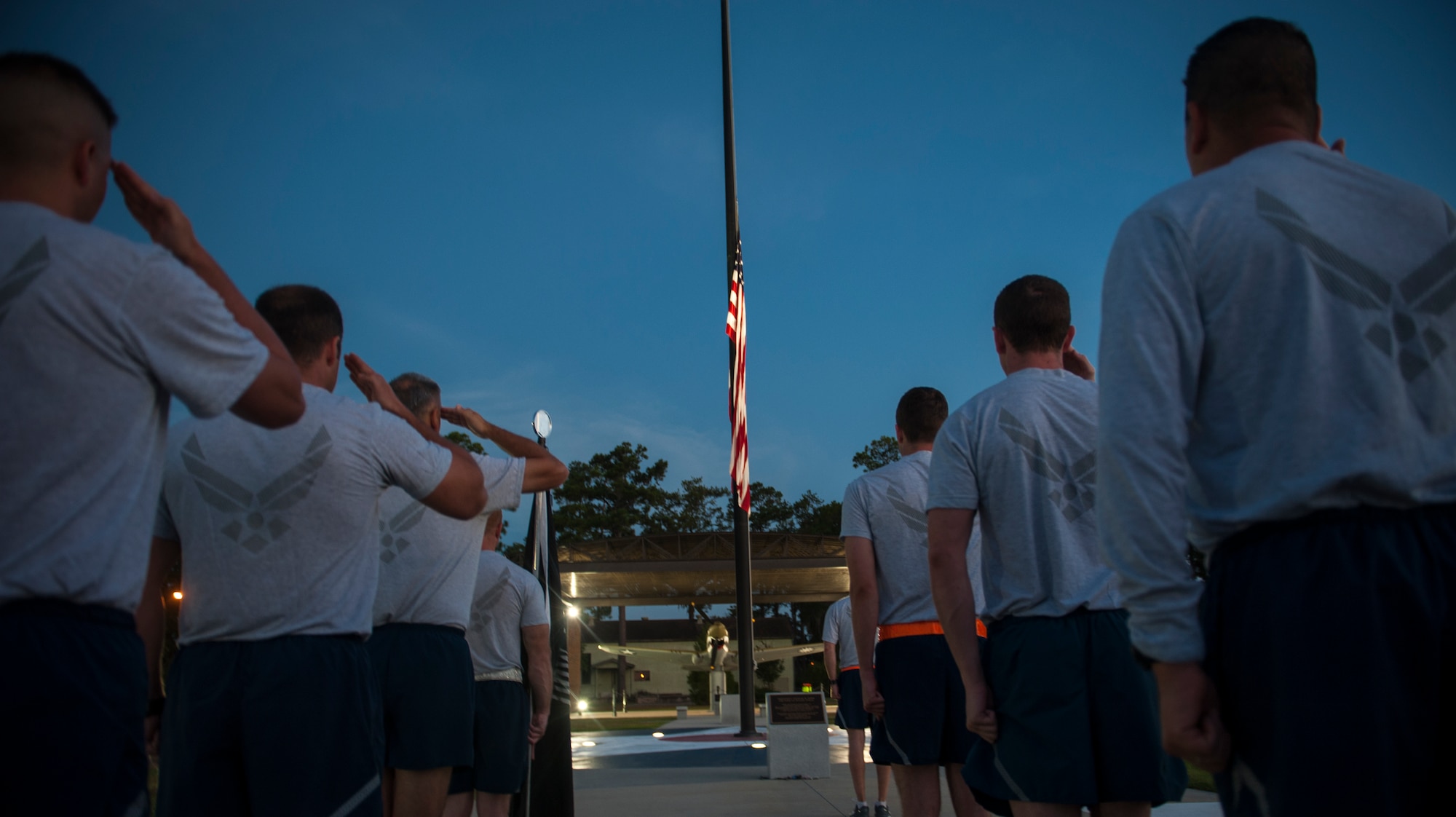 Airmen stand at attention and salute the flag for reveille at Moody Air Force Base, Ga., Sept. 20, 2013. Airmen from the base participated in a 23-mile run in support of the men and women who were and are Prisoners of War or Missing in Action. (U.S. Air Force photo by Airman Alexis Grotz/Released)