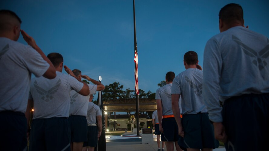 Airmen stand at attention and salute the flag for reveille at Moody Air Force Base, Ga., Sept. 20, 2013. Airmen from the base participated in a 23-mile run in support of the men and women who were and are Prisoners of War or Missing in Action. (U.S. Air Force photo by Airman Alexis Grotz/Released)