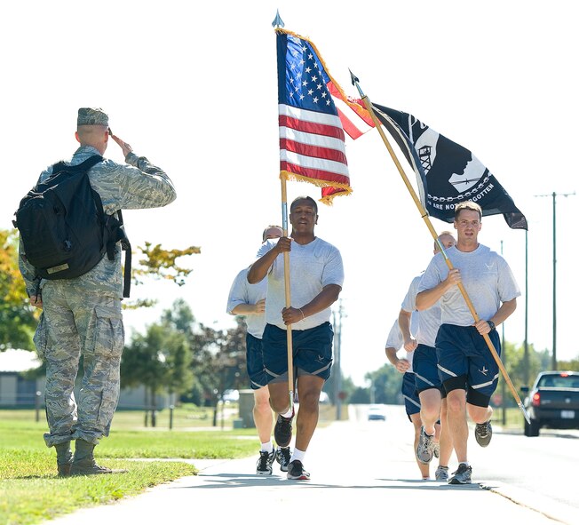 A Team Dover member salutes as runners pass by with the U.S. and prisoner of war/missing in action flags Sept. 20, 2013, at Dover Air Force Base, Del. Airmen ran for a total of 24 hours with the flags in shifts of 15 minutes. (U.S. Air Force photo/Roland Balik)