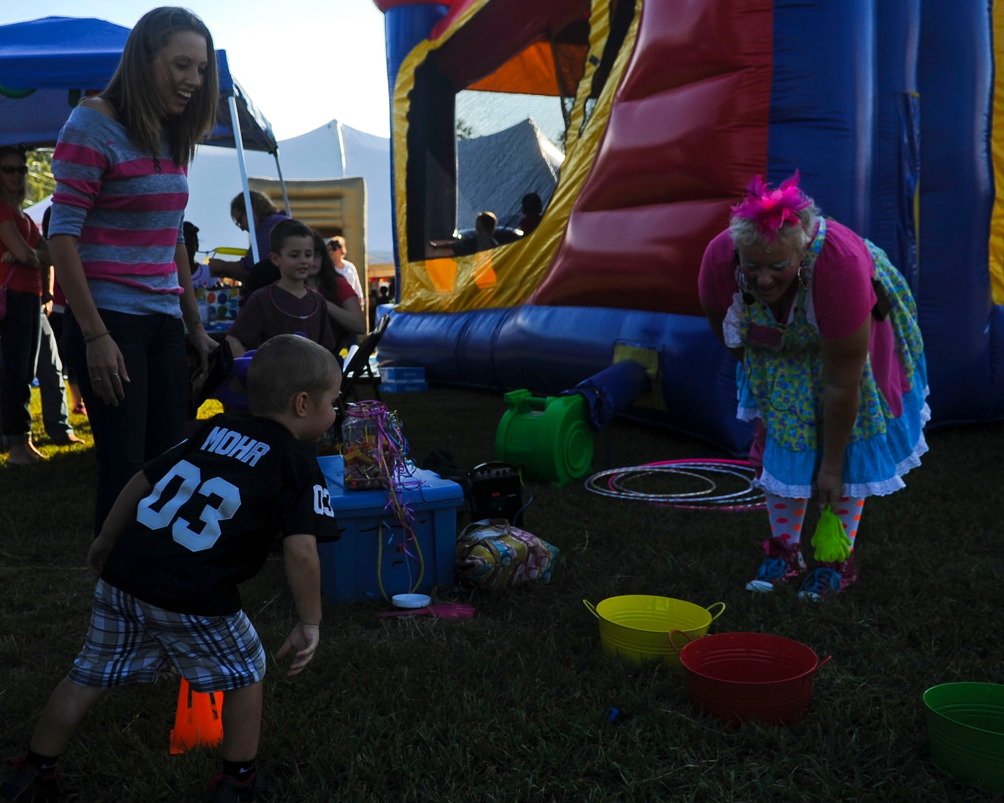 Valerie Tutson, an entertainer, assists a boy during one of many mini-games offered to children during Oktoberfest at Fort Eustis, Va., Sept. 20, 2013. Children also had an opportunity to participate in arts and crafts the next day during the Fall Festival, or “Kinderfest.”(U.S. Air Force photo by Airman 1st Class Austin Harvill/Released)