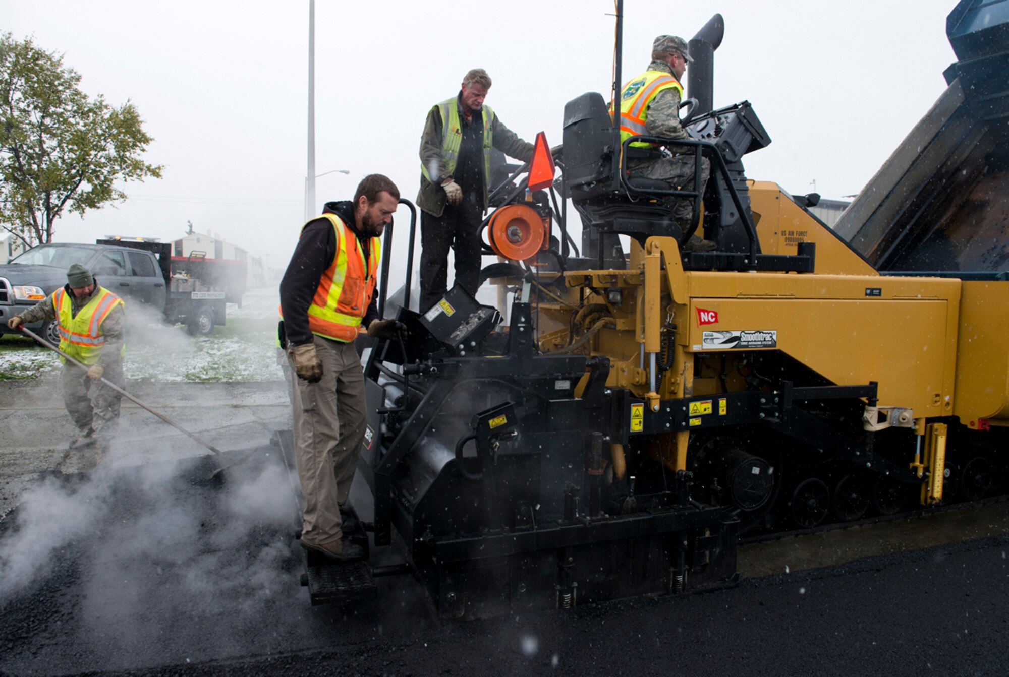 Members of the 773d Civil Engineer Squadron lay down pavement near the People Center on Joint Base Elmendorf-Richardson, Sept. 23, 2013. This is one of the earliest snowfalls in the last 20 years in Anchorage and despite the snow, the 773 CES was out repairing this road. (U.S. Air Force photo/Staff Sgt. Zachary Wolf)