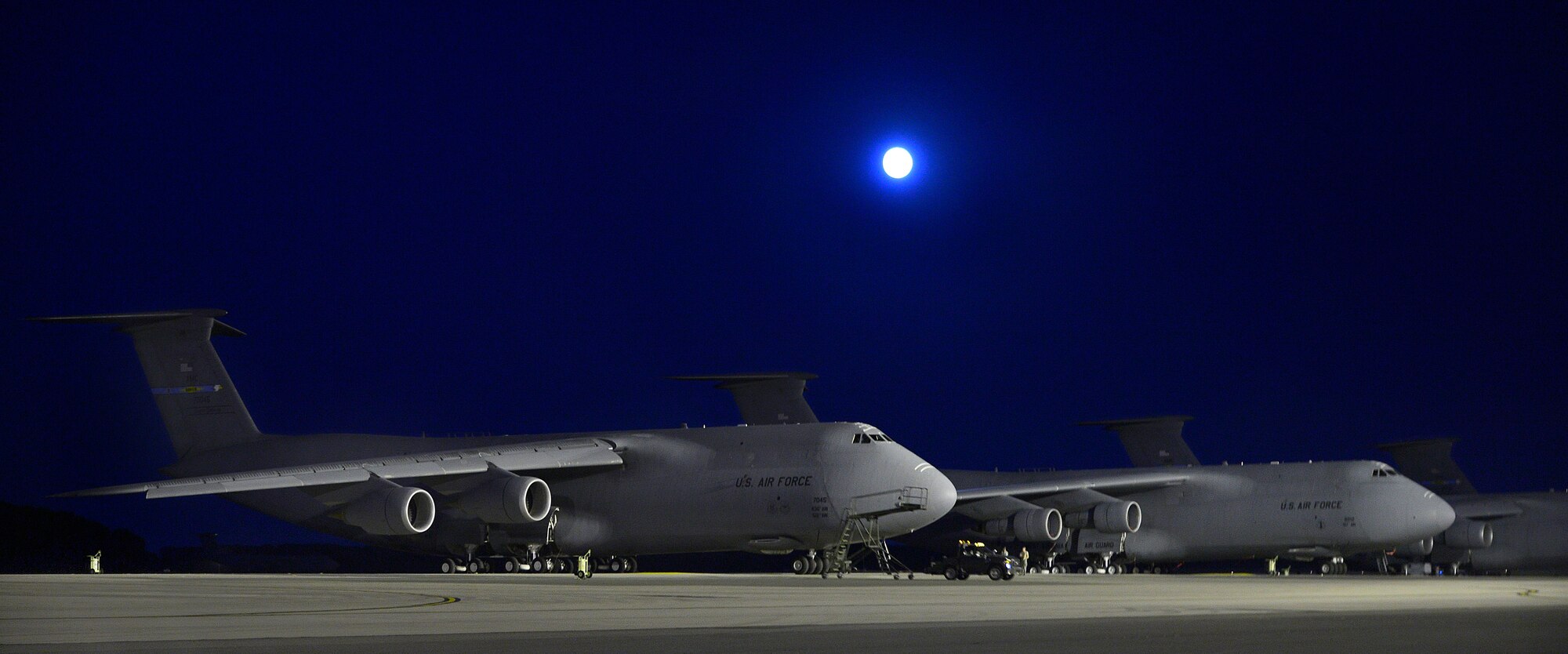 A C-5M and C-5A Super Galaxies sit on the runway at night Sept 19, 2013, at Dover Air Force Base, Del. The C-5M is an upgraded version of the C-5 with new engines and modernized avionics designed to extend its life beyond 2040. The full moon not only made for a well-lit night on the flight line, it also illuminated the astonishing upgrades and features of the C-5M. (U.S. Air Force photo/David Tucker)