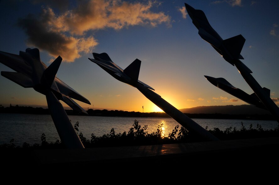 The sunset catches the silhouette of a statue of the missing man formation at Joint Base Pearl Harbor-Hickam, Hawaii as the sun sets over the waters of Pearl Harbor, Hawaii.  (U.S. Air National Guard photo by Master Sgt. Kendra M. Owenby, 134 ARW Public Affairs/Released)