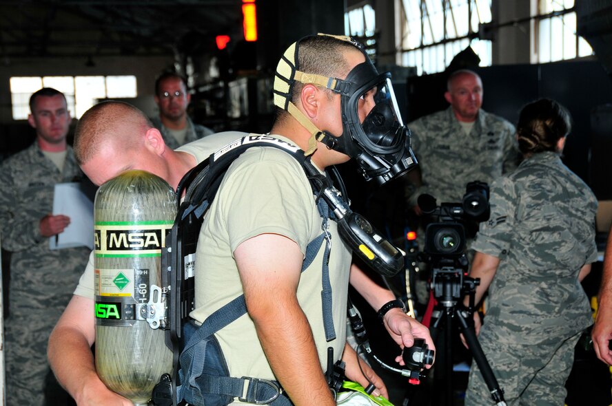 Airman First Class Brad Daugherty adjusts the air tank on a Level A suit for Senior Airman Johnny Romines as other members of the 134th Air Refueling Wing Civil Engineer Squadron Emergency Management team look on during a a training exercise at Joint Base Pearl Harbor- Hickam, Hawaii August 03-17.  (U.S. Air National Guard photo by Master Sgt. Kendra M Owenby/Released)