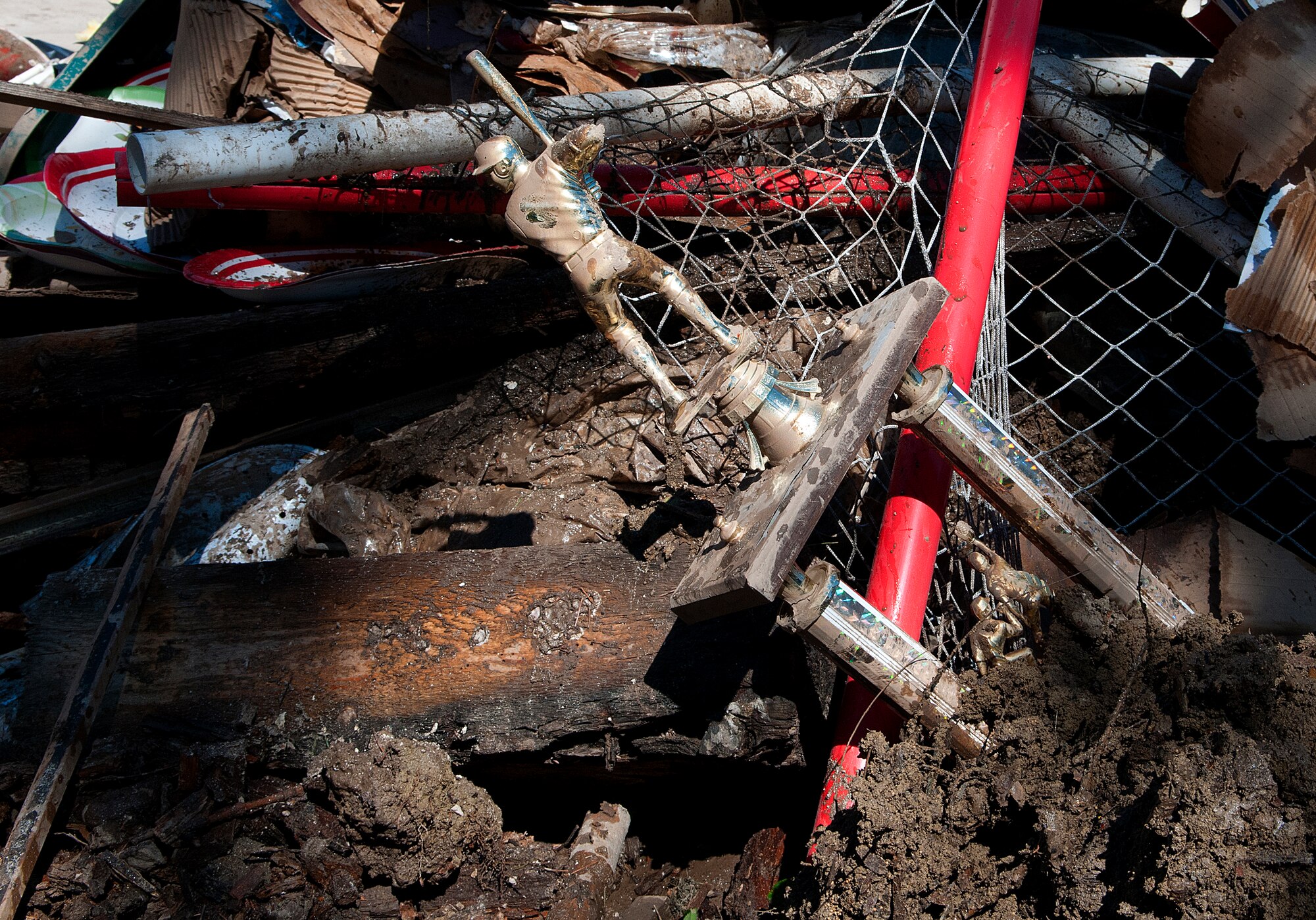 A sports trophy and other ruined possessions lay in a rubbish pile caked in mud outside a Longmont, Colo., home Sept. 21, 2013. Airmen with the 90th Missile Wing, F.E. Warren Air Force Base, Wyo., volunteered to give up a day off to help the victims of the northern Colorado flood. (U.S. Air Force photo by R.J. Oriez)
