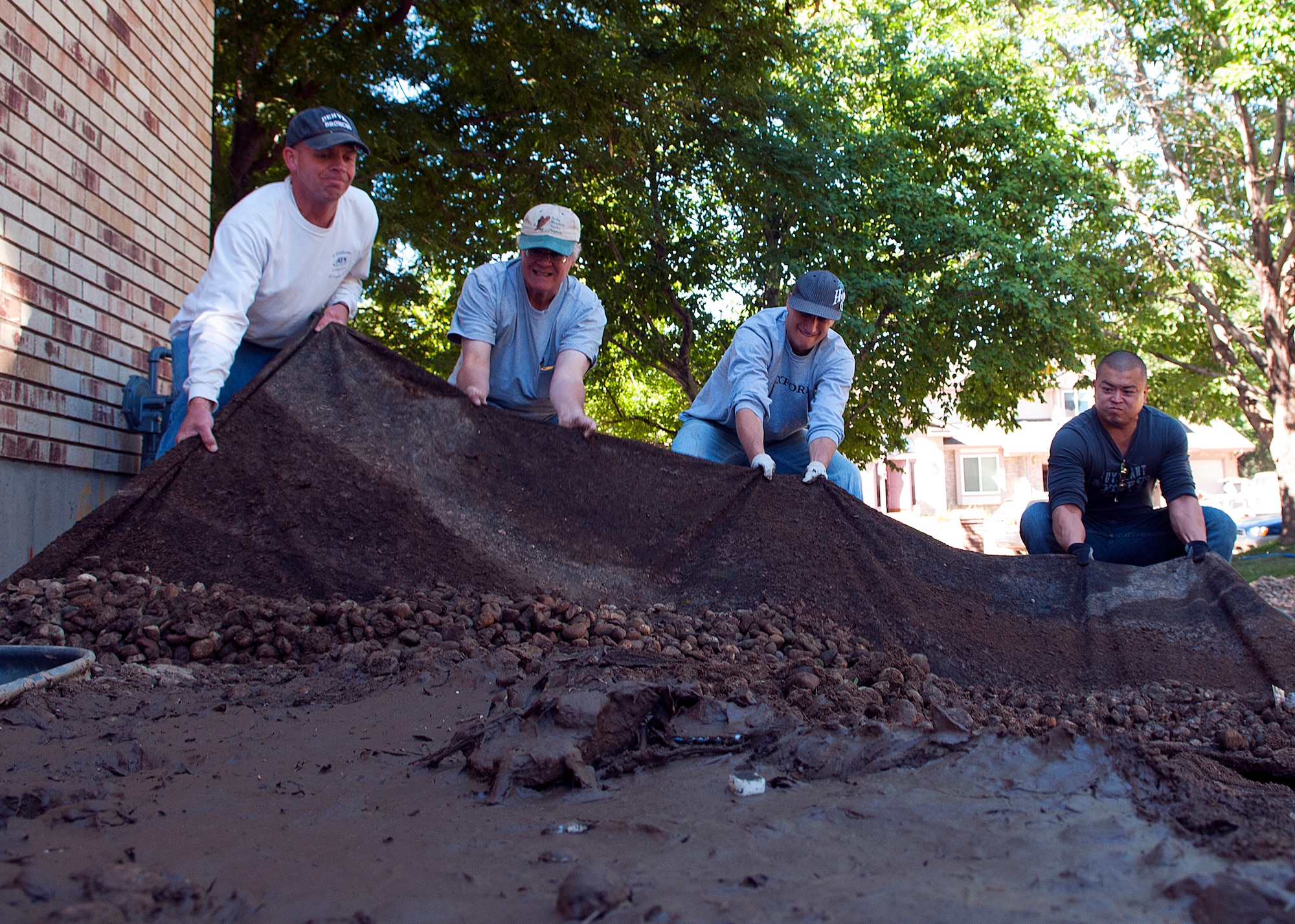 Maj. Darrel Johnson, left, a local homeowner, and Staff Sgts. Sean Massar and Rich Lew, struggle to repair landscaping destroyed by flooding in Longmont, Colo. Johnson led a volunteer group of F.E. Warren Air Force Base, Wyo., Airmen down to the Northern Colorado community Sept. 21, 2013 to assist the victims of recent flooding.  (U.S. Air Force photo by R.J. Oriez)