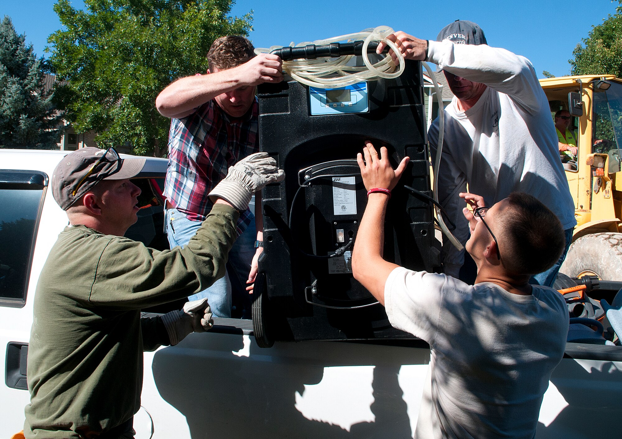 Tech. Sgt. Jessie Daughtry, 90th Missile Wing Protocol office, Airman 1st Class Donald Neal, 90th Civil Engineer Squadron structure shop, and Maj. Darrel Johnson, 90th Missile Wing command post director, help Jamie McVaney unload a dehumidifier from his truck in a flood-damaged Longmont, Colo., neighborhood Sept. 21, 2013. The dehumidifier will be used to help dry out basements to prevent mold. (U.S. Air Force photo by R.J. Oriez)