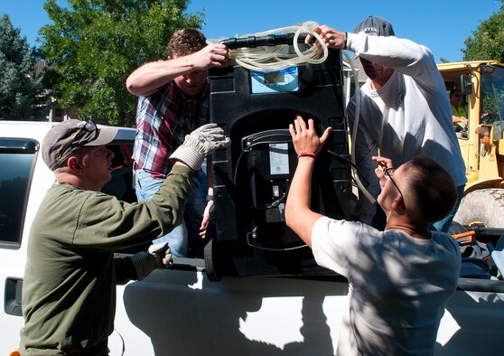 Tech. Sgt. Jessie Daughtry, 90th Missile Wing Protocol office, Airman 1st Class Donald Neal, 90th Civil Engineer Squadron structure shop, and Maj. Darrel Johnson, 90th Missile Wing command post director, help Jamie McVaney unload a dehumidifier from his truck in a flood-damaged Longmont, Colo., neighborhood Sept. 21, 2013. The dehumidifier will be used to help dry out basements to prevent mold. (U.S. Air Force photo by R.J. Oriez)