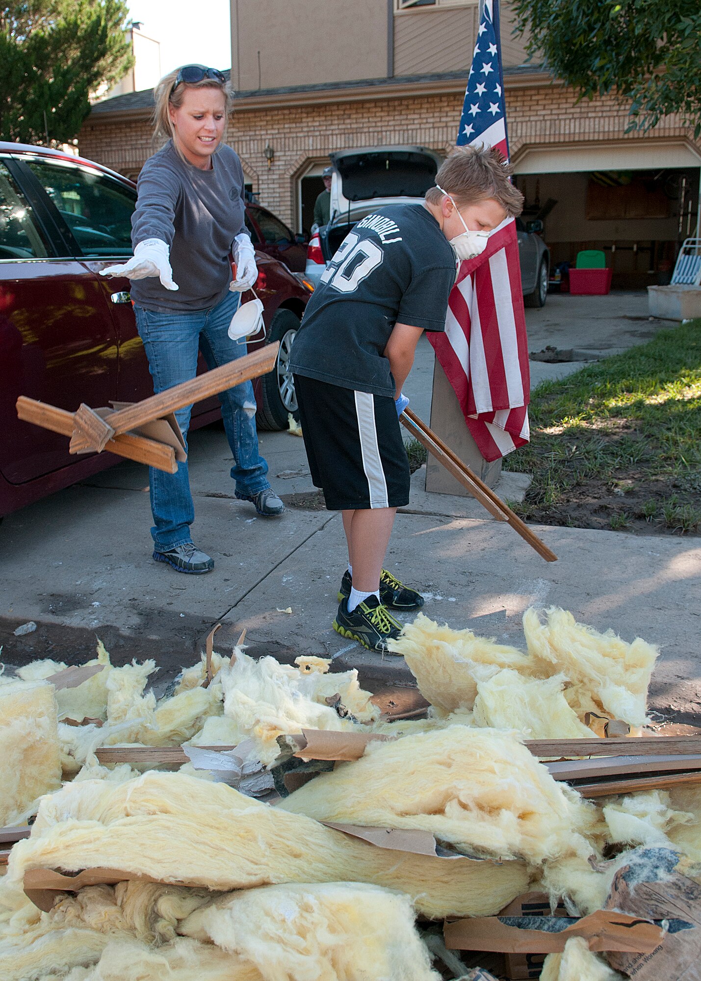 Tech. Sgt. April Barbett, 90th Missile Wing command post, and Jacob Moats, 8, throw debris from Moats’ flood-damaged home on the trash pile Sept. 21, 2013. Barbett joined a group of F.E. Warren Air Force Base, Wyo., Airmen who volunteered to travel to Longmont, Colo., to help victims of the Northern Colorado flood. (U.S. Air Force photo by R.J. Oriez)