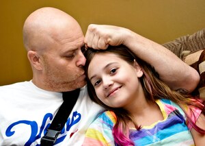 U.S. Army Staff Sgt. John Bilyeu an instructor with the 210th Aviation Regiment at Fort Eustis, Va., kisses his 12-year-old daughter Sierra inside their Newport News home, Sept. 9, 2013. Sierra saved Bilyeu's life when she called 911 after he had an allergic reaction to a bee sting Aug. 24, 2013. (U.S. Air Force photo by Staff Sgt. Wesley Farnsworth/Released)