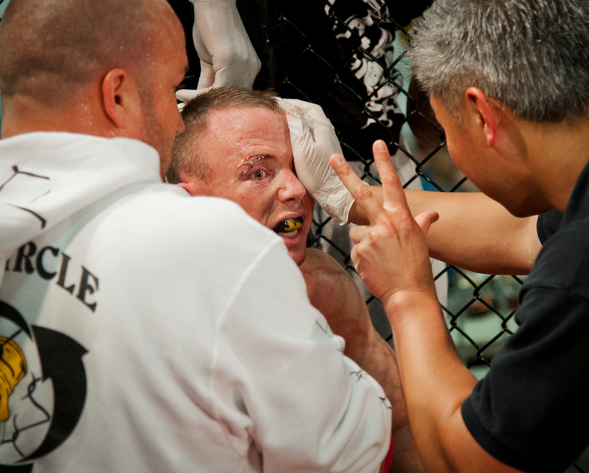 A mixed martial arts expert evaluates Tony Conners eyesight after he was cut above the eye in the previous round against Michael Roberts during Strike Fight II Sept. 21 at Eglin Air Force Base, Fla.  Roberts won the fight with a rear-naked choke hold.  Conners is a Marine and Roberts is active-duty Navy. This was Eglin’s second mixed martial arts event.   (U.S. Air Force photo/Samuel King Jr.)