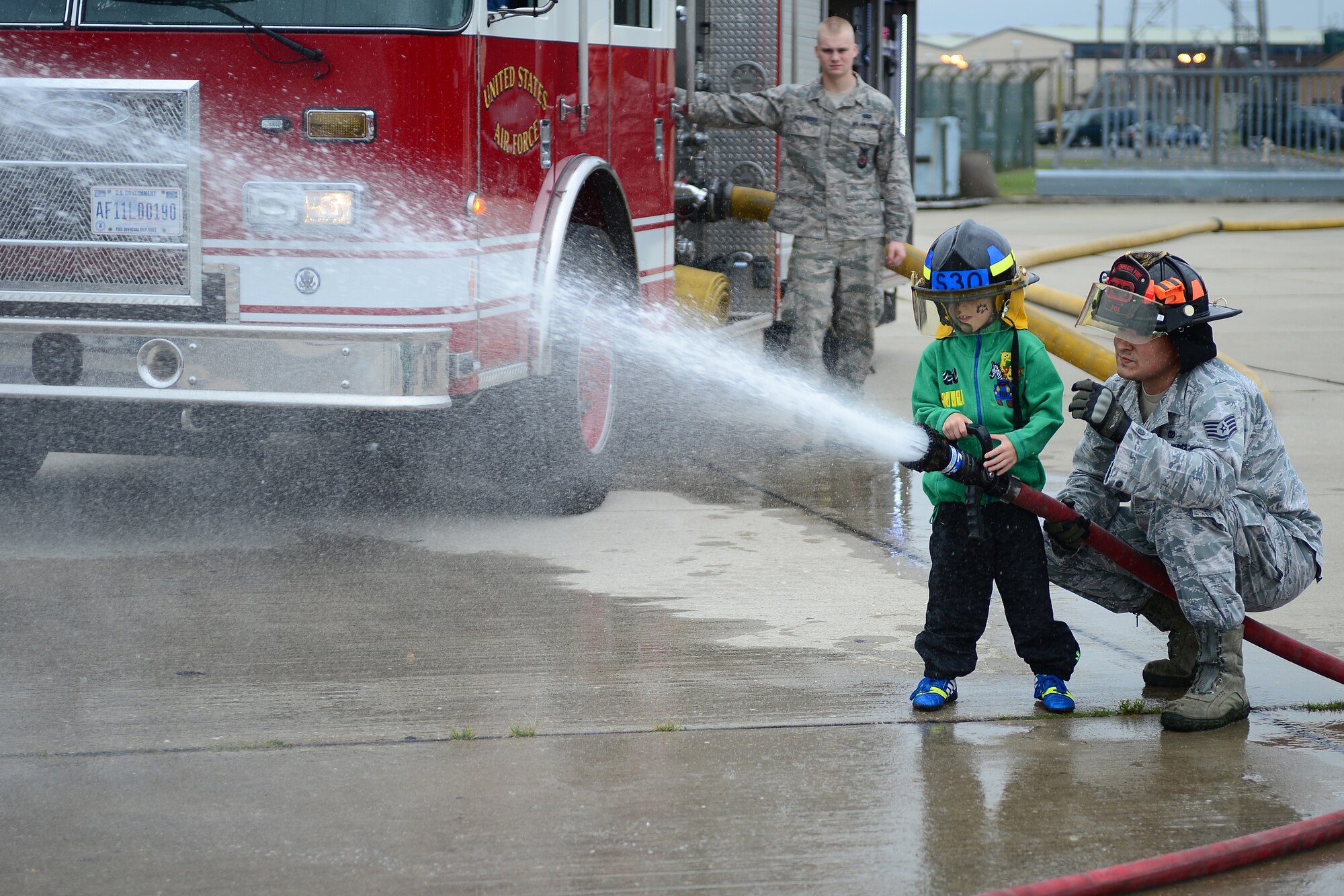 Staff Sgt. Nicholas Fox, 48th Civil Engineer Squadron Fire Department crew chief, helps Toby Hayward,7, spray a fire hose at Royal Air Force Lakenheath, England, Sept. 21, 2013. More than 30 children from East Anglia’s Children’s Hospices, and their families, were invited to Children’s Hospice Family Day, which allowed children in hospice care and their families a day of fun and a break from routine doctor and hospital visits. (U.S. Air Force photo by Airman 1st Class Dana J. Butler/Released)