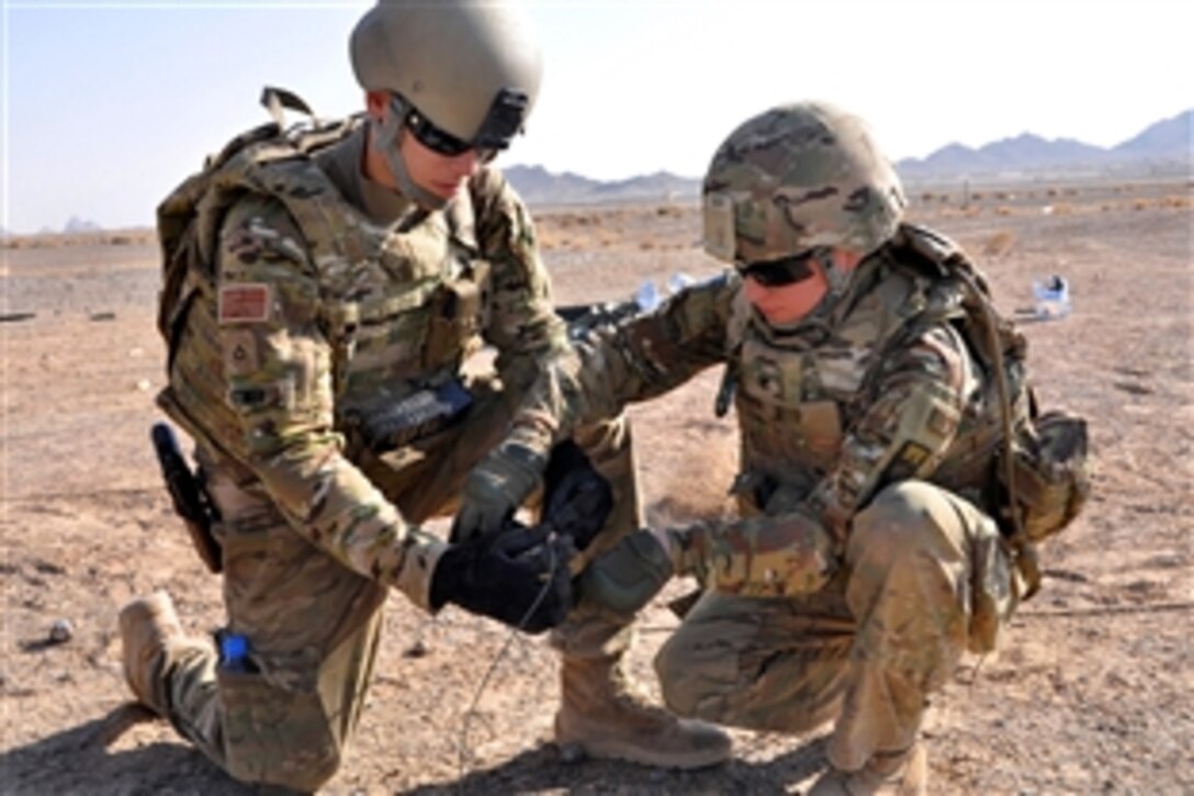 U.S. Army Pfc. Bittner, left, and U.S. Navy Petty Officer 3rd Class Ashley North use tape to wrap detonation cord during weapons and explosives training at the range on Forward Operating Base Farah, Afghanistan, Sept. 20, 2013. Bittner is assigned to the 1st Infantry Division's Company B, 3rd Brigade, 2nd Battalion 1st Infantry Regiment, and North, an operations specialist, is assigned to Provincial Reconstruction Team Farah.