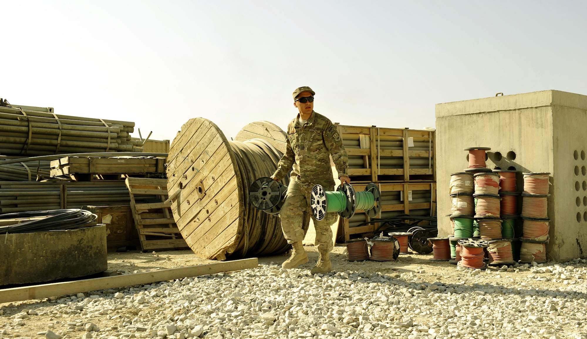 Senior Airman Randel Gutierrez, 455th Expeditionary Communications Squadron member, picks up copper cables from the storage yard on Bagram Airfield, Afghanistan. Gutierrez is deployed from Hill Air Force Base, Utah.