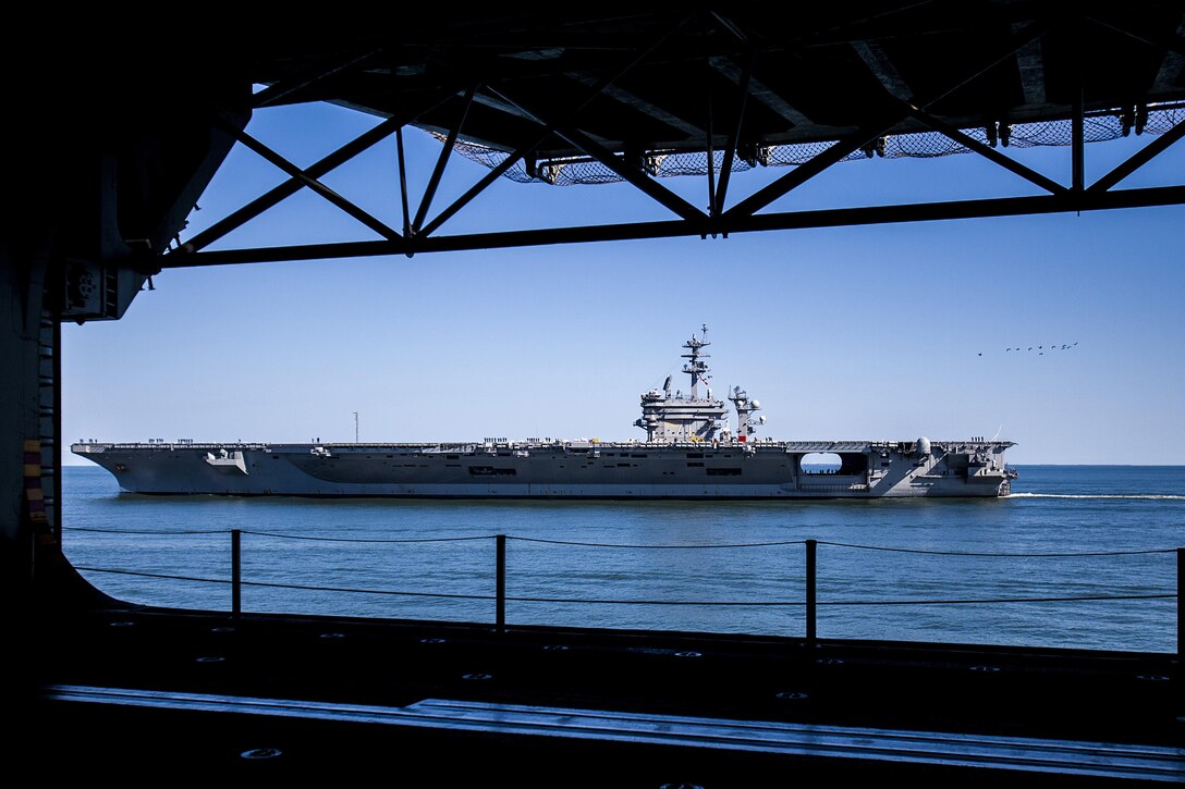 The aircraft carrier USS Theodore Roosevelt (CVN 71) and amphibious assault ship USS Bataan (LHD 5) render honors to each other off the coast of Norfolk, Va., during the 22nd Marine Expeditionary Unit (MEU)'s PHIBRON/MEU Integration Training (PMINT) exercise Sept. 20, 2013. PMINT is the 22nd MEU's first opportunity to work aboard the Bataan as a composited MEU since the MEU's 2011 deployment. The MEU is scheduled to deploy in early 2014 to the U.S. 5th and 6th Fleet areas of responsibility with the Bataan Amphibious Ready Group as a sea-based, expeditionary crisis response force capable of conducting amphibious missions across the full range of military operations. (U.S. Marine Corps photo by Sgt. Austin Hazard/Released)