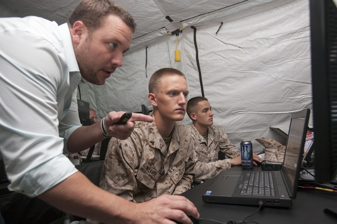 Nathan Poole, chief operations instructor for the Common Aviation Command Control System Phase I, shows Lance Cpl. Ethan Weaver, an air control electronics operator, Marine Air Control Squadron 24, how to navigate a portion of the Common Aviation Command Control System (CAC2S). The MACS-24 Marines received in depth training on the new system as a part of Phase I of the CAC2S program.