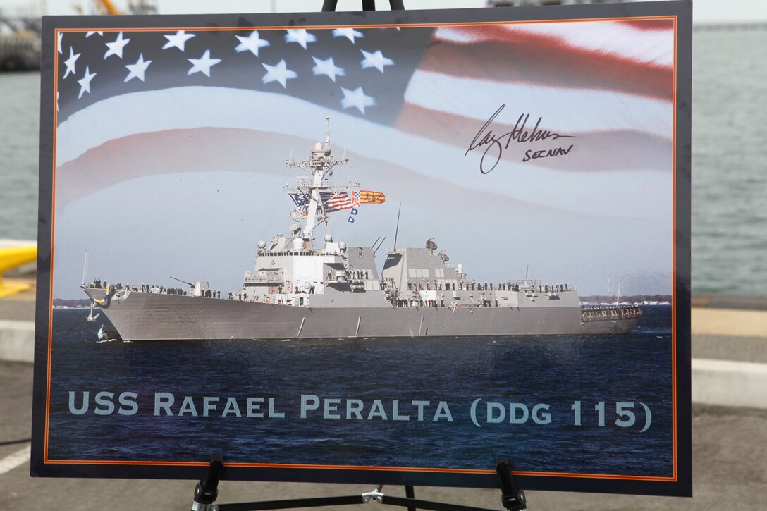 A photo of the newly named 65th Arleigh Burke-class destroyer is displayed during a ship naming ceremony aboard Naval Base San Diego, Calif., Sept. 20.  The USS Rafael Peralta was named after Navy Cross recipient Sgt. Rafael Peralta, who is credited with absorbing the impact of a grenade while fatally wounded to save the lives of his Marines during intense fighting in Fallujah, Iraq, in November 2004.