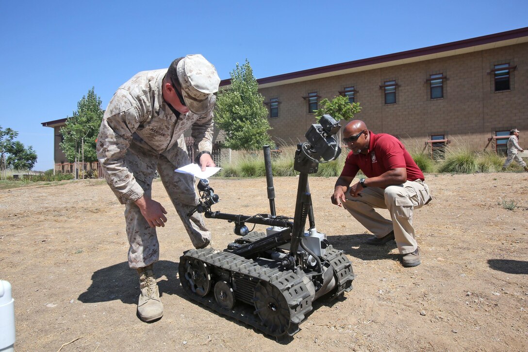 Craig Burnett, right, a civilian technician and trainer with Robotic Systems Joint Project Office, teaches Cpl. Michael J. Mangan, a combat engineer from Alpha Company, 7th Engineer Support Battalion, 1st Marine Logistics Group, how to operate a Foster-Miller TALON robot aboard Camp Pendleton, Calif., Sept. 12, 2013. The robots are used for different tasks, such as identifying objects from far distances, placing charges to blow up improvised explosive devices in place, and handling smaller objects with precision.