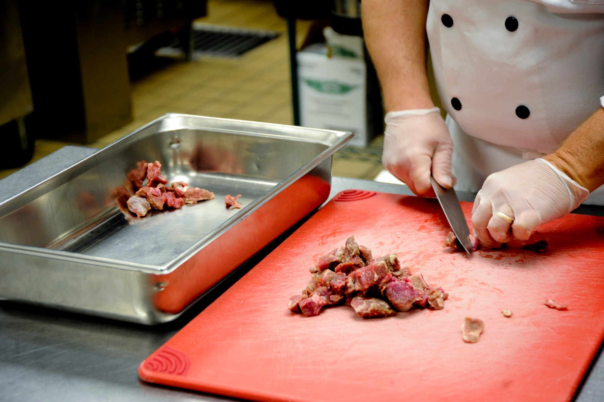 Michael Soich, Desert Inn cook, cuts pieces of meat at Davis-Monthan Air Force Base, Ariz., Sept. 24, 2013. Soich helps with food preparation and educates the Airman about proper temperature, food handling, disease prevention, food quality and sanitation. (U.S. Air Force photo by Airman 1st Class Justin Veazie/Released)