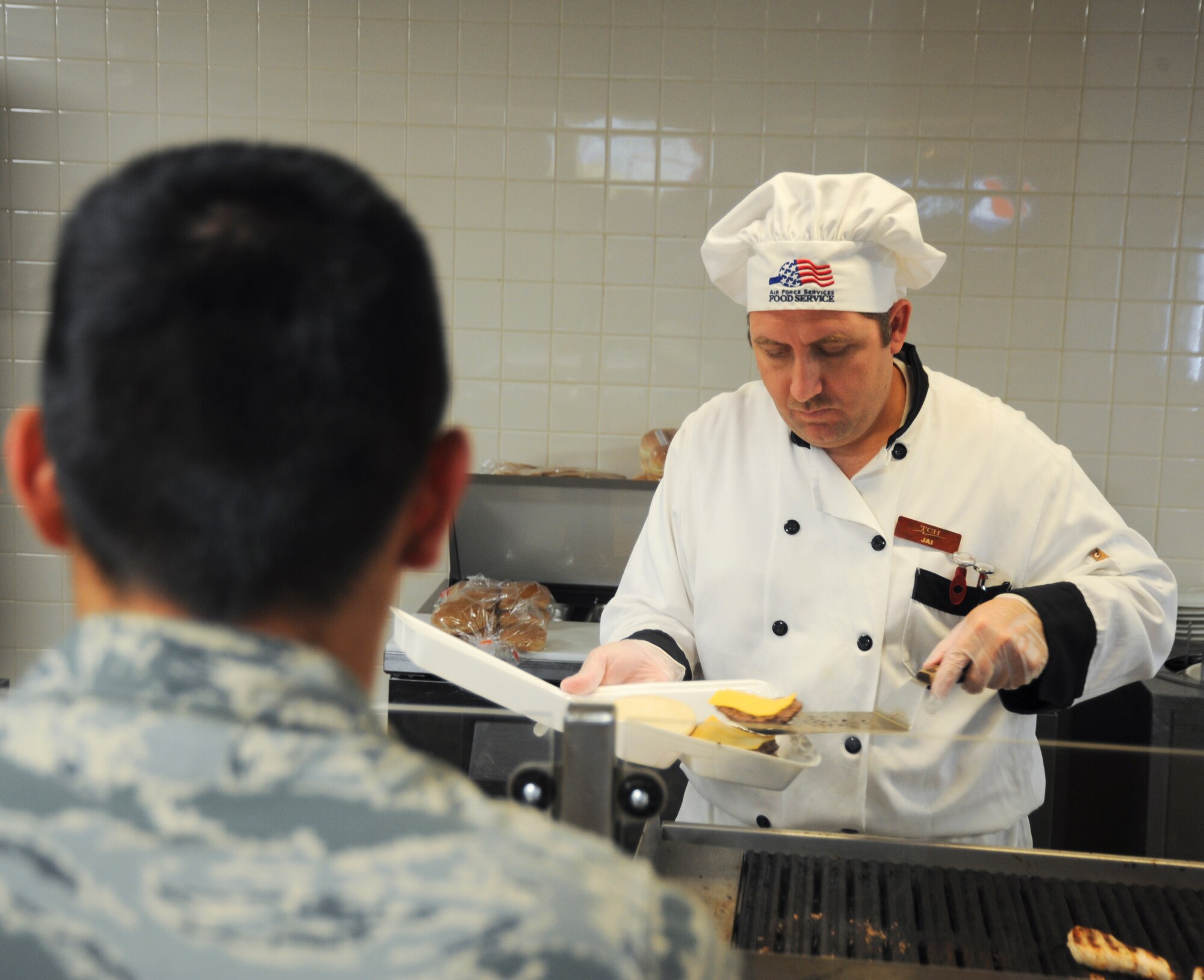 Jai Williams, Desert Inn cook, serves an Airman food at Davis-Monthan Air Force Base, Ariz., Sept. 24, 2013. On average the Desert Inn serves more than 700 dorm residents daily. (U.S. Air Force photo by Airman 1st Class Justin Veazie/Released)