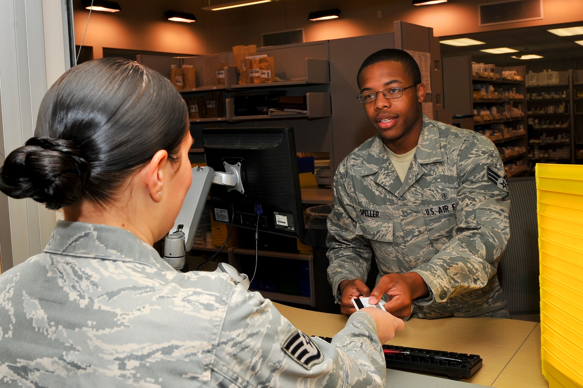 Senior Airman Devonte Speller, 460th Medical Group pharmacy technician, receives an ID from a Team Buckley member Sept. 24, 2013, at the pharmacy on Buckley Air Force Base, Colo. Speller has been nominated by Air Force Space Command for the Lance P. Sijan Award awarded to Airmen for exceptional leadership in all aspects of life. (U.S. Air Force Photo by Senior Airman Phillip Houk/Released)
