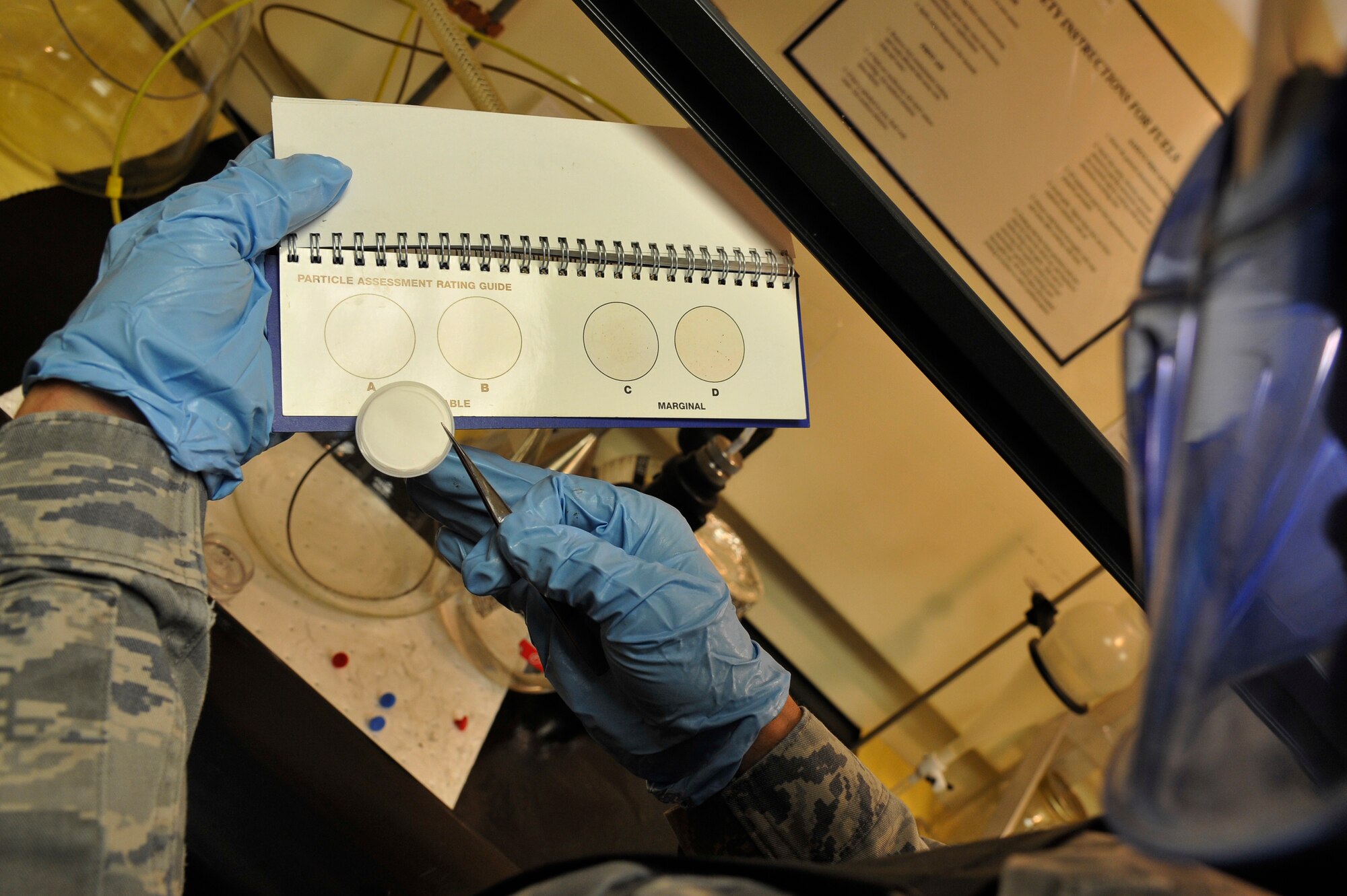 Tech. Sgt. Ronald Gasper compares a filter membrane against a standard rating guide to determine particle assessment of a fuel sample Sept. 17, 2013, Scott Air Force Base, Ill. The rating system helps determine if fuel is acceptable to use. Gasper is the noncommissioned officer in charge of the fuels laboratory assigned to the 375 Logistics Readiness Squadron. (U.S. Air Force photo/Staff Sgt. Christopher Boitz)