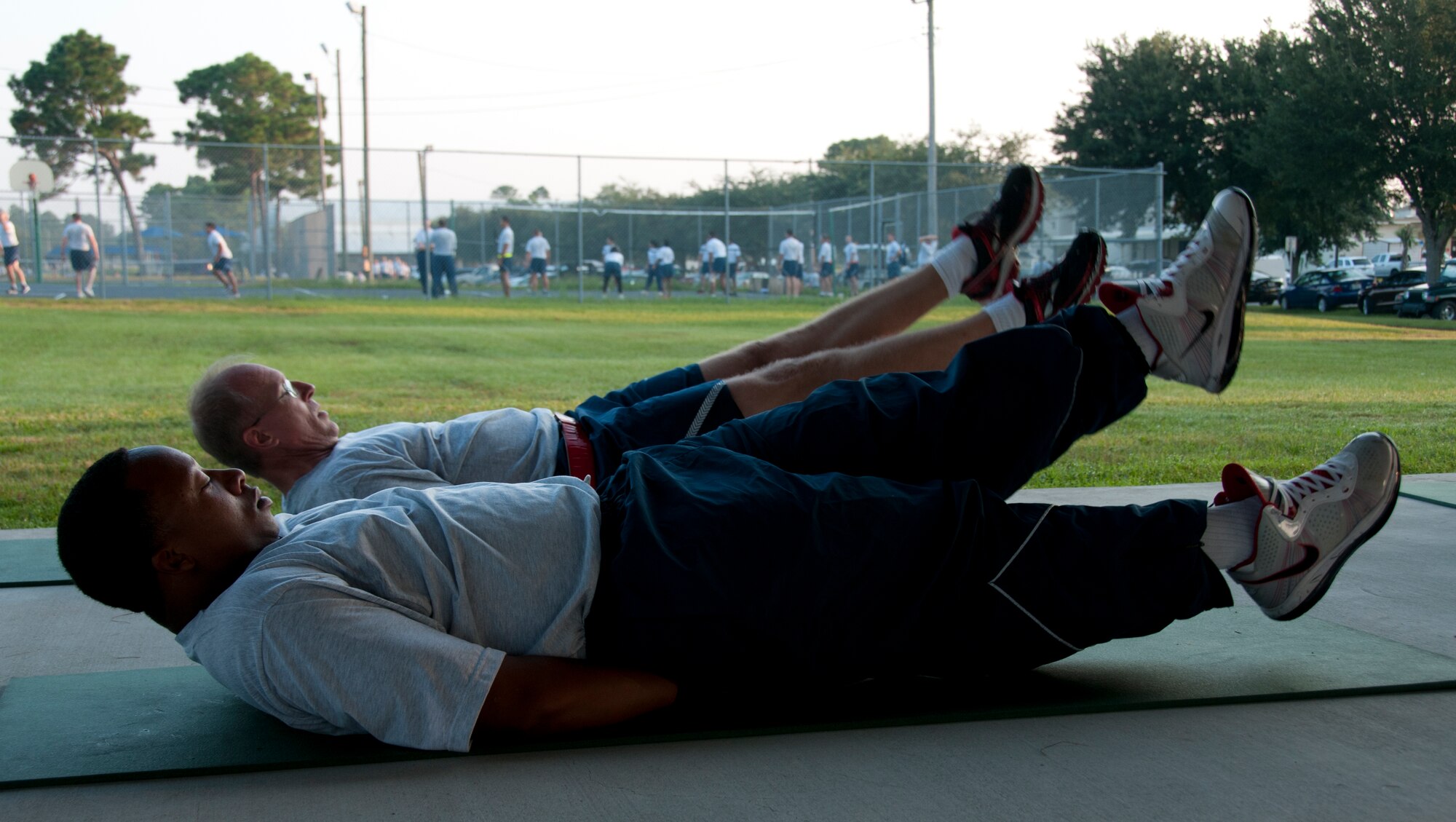 Air Force Reserve Tech. Sgt. Tremain Strong, left, and Senior  Master Sgt. David Parcher, from the 919th Maintenance Squadron, perform flutter kicks during a unit physical training session at Duke Field, Fla., Sept. 7.  The squadron begins each monthly unit training assembly with a mass stretching and calisthenics session before releasing members to finish individual workouts such as running, weight training, basketball, volleyball and more. (U.S. Air Force photo/Tech. Sgt. Jasmin Taylor) 