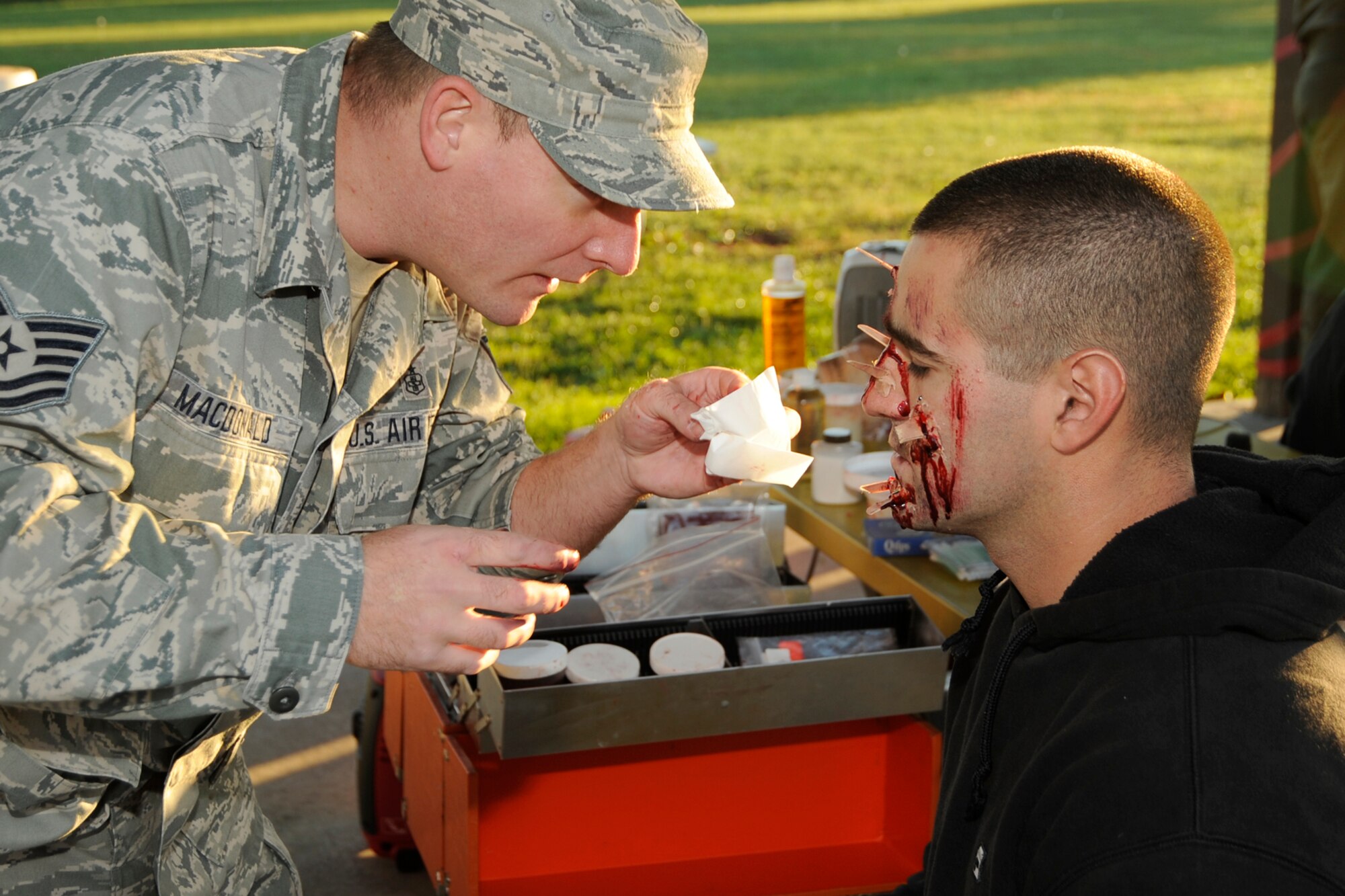 130924-H-HC784-007 Prior to the Major Accident Response Exercise at Selfridge Air National Guard Base, Mich., September 24, 2013 , those who volunteered to play the role of casualties were moulaged to have are realistic effect. Tech Sgt. Brad Macdonald of the 127th Medical Group preparing volunteer casualty Airman 1st Class Bryan Doroujalian from the 127th Civil Engineer Squadron
 with shrapnel wounds to the face due to the simulated bomb explosion. (U.S. Air National Guard photo by John Swanson/Released)
