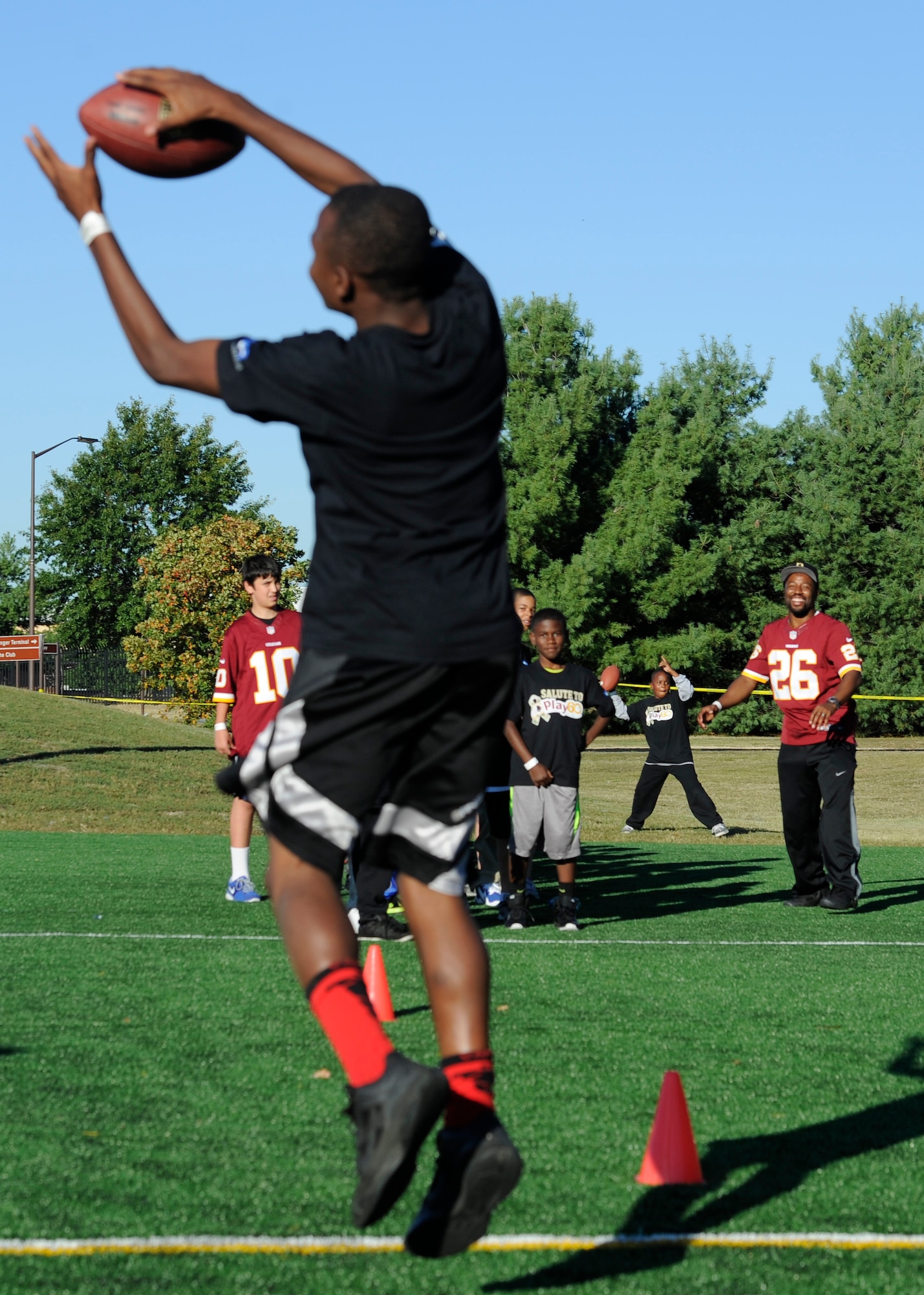 Washington Redskins cornerback Jason Wilson throws a football to a military child during the Salute to Play 60 Military Challenge at Joint Base Andrews, Md., Sept. 24, 2013. Play 60 kick-started a challenge encouraging hundreds of military families in the National Capital Region to track daily activity for four weeks. At the conclusion of the challenge the children with the highest level of participation will be recognized by the Washington Redskins organization. (U.S. Air Force photo/ Airman 1st Class Nesha Humes)