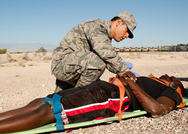 Tech Sgt. Hugo Silva, 99th Medical Operations Squadron medical technician, checks a simulated patient for additional injuries Sept. 19, 2013, near the Mike O’ Callaghan Federal Medical Center during an aircraft crash response exercise at Nellis Air Force Base, Nev.  Airmen from the 99th MDOS arrived at several simulated accident scenes to provide medical treatment and transportation to the federal  medical center for simulated victims. (U.S. Air Force photo by Staff Sgt. Michael Charles)