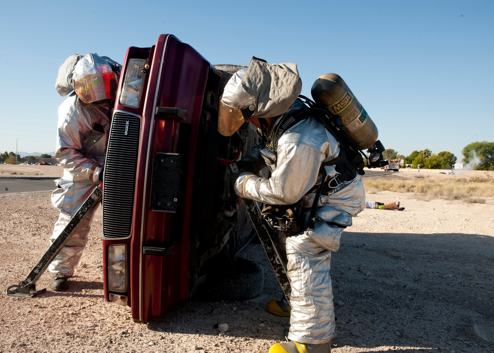 Two Airmen from the 99th Civil Engineer Squadron Fire Department stabilize a car for an emergency extraction Sept. 19, 2013, near the Mike O’ Callaghan Federal Medical Center during an aircraft crash response exercise at Nellis Air Force Base, Nev.  Before extracting trapped people from a rolled-over car, first responders are required to ensure the vehicle no longer has the potential to cause further injury. (U.S. Air Force photo by Staff Sgt. Michael Charles)