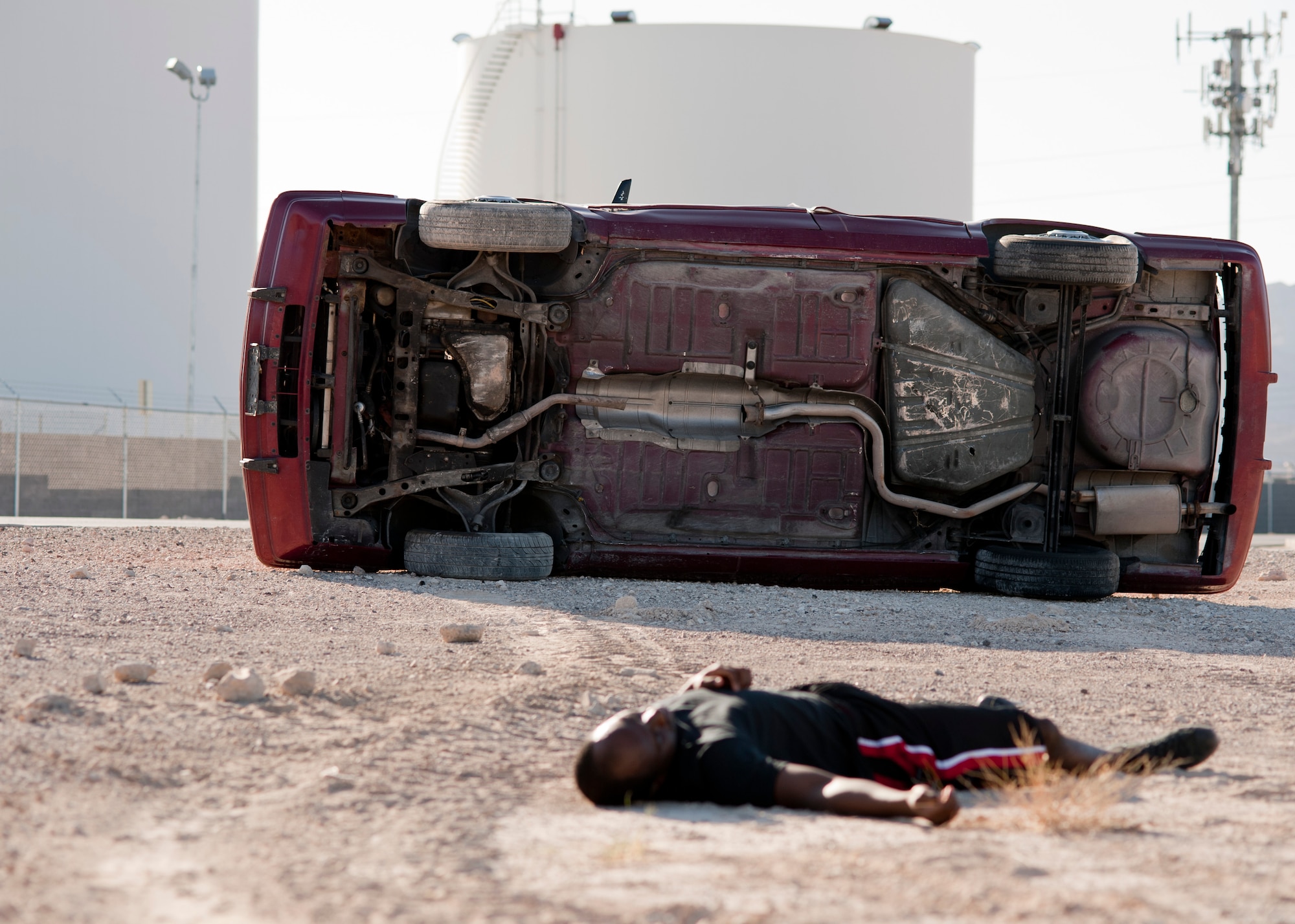 A simulated victim lies on the ground beside a wrecked car Sept. 19, 2013, near the Mike O’ Callaghan Federal Medical Center during an aircraft crash response exercise at Nellis Air Force Base, Nev.  The scenario was an aircraft had an inflight emergency and broke up on the way down.  Parts of the aircraft “hit” vehicles driving on Range Road. The exercise tested Airmen, contractors and civilians in their response to a major aircraft incident. (U.S. Air Force photo by Staff Sgt. Michael Charles) 