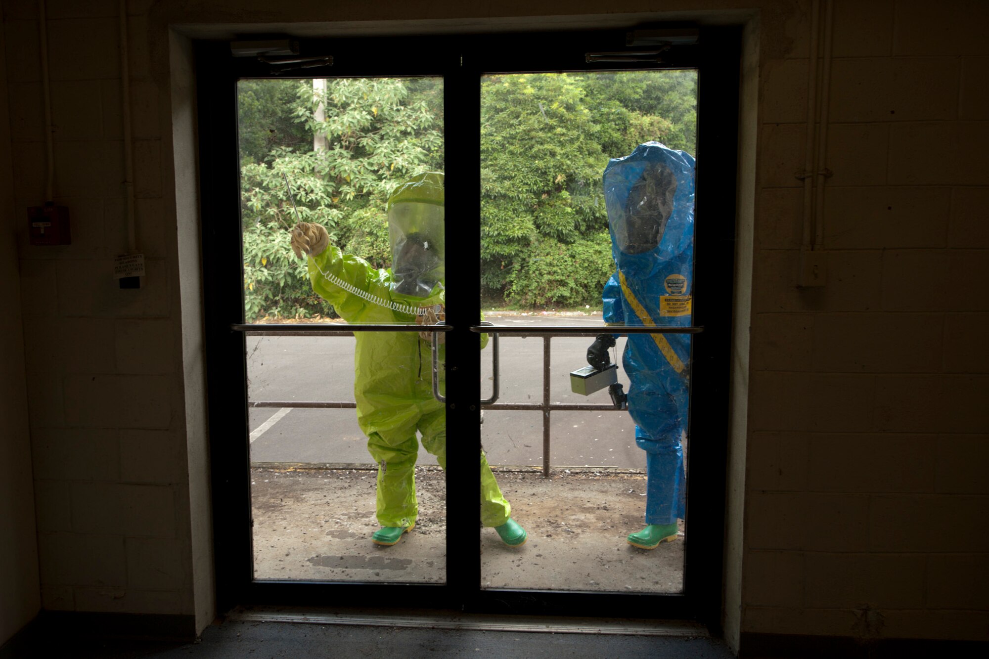 U.S. Air Force Senior Airman Devon de Castrique (left), 65th Medical Operations Squadron environmental health manager, and Staff Sgt. Samuel Helfrich, 65th Civil Engineer Squadron emergency management technician, wear fully-encapsulated hazmat suits while they test the exterior doors of a building for hazardous materials during a joint biological response training exercise Sept. 20, 2013, at Lajes Field, Azores. The suits allow the technicians to safely perform the required tests in a biological environment with the ability to remain protected and breath clean air. The exercise is to test the effectiveness of emergency managers and bioenvironmental engineers working together in a crisis situation, maintain proficiency in duties, and identify strength or improvement capabilities. De Castrique is from Charlotte, N.C., and Helfrich is from San Clemente, Calif. (U.S. Air Force photo by Tech. Sgt. Paul Villanueva II/Released)