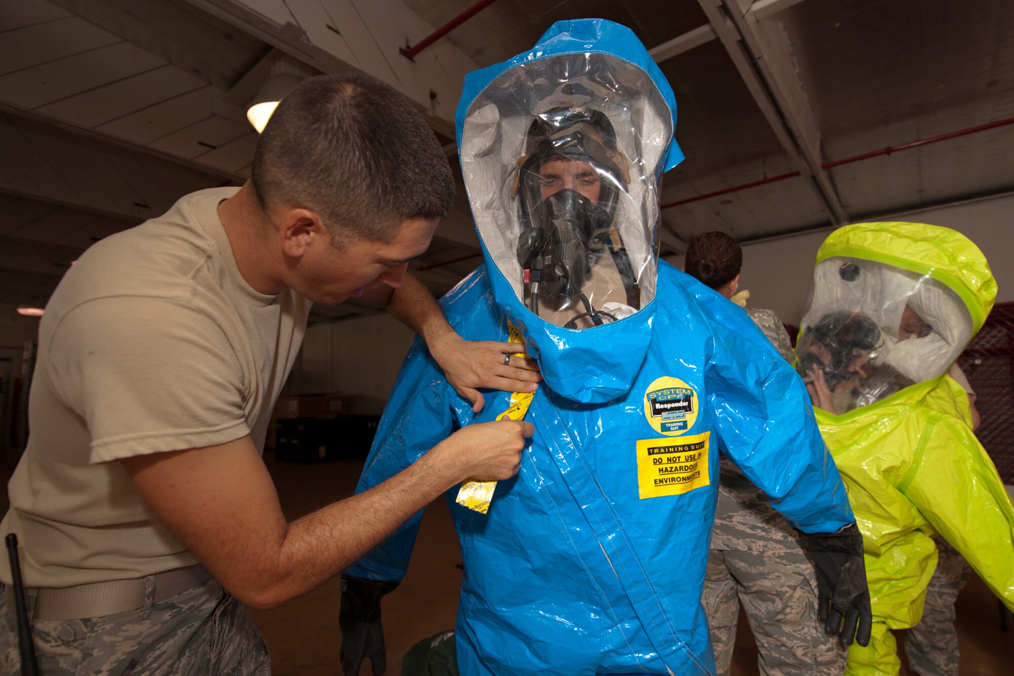 U.S. Air Force Staff Sgt. James Goeddey, 65th Civil Engineer Squadron Plans and Operations non-commissioned officer in charge, tapes closed a fully-encapsulated hazmat suit worn by Staff Sgt. Samuel Helfrich, 65th CES emergency management technician, during a joint biological response training exercise Sept. 20, 2013, at Lajes Field, Azores. The suits allow the technicians to safely perform the required tests in a biological environment with the ability to remain protected and breath clean air. The exercise is to test the effectiveness of emergency managers and bioenvironmental engineers working together in a crisis situation, maintain proficiency in duties, and identify strength or improvement capabilities. (U.S. Air Force photo by Tech. Sgt. Paul Villanueva II/Released)