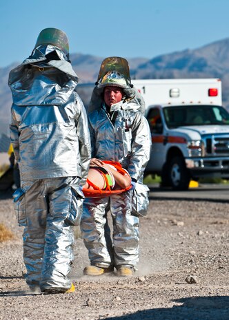 Airmen from the 99th Civil Engineer Squadron Fire Department carry a simulated victim Sept. 19, 2013, near the Mike O'Callaghan Federal Medical Center to a waiting ambulance during a major aircraft crash response exercise at Nellis Air Force Base, Nev. Simulated victims were assessed for their medical condition on scene and transported to Mike O'Callaghan Federal Medical Center for further treatment. (U.S. Air Force photo/Senior Airman Brett Clashman)
