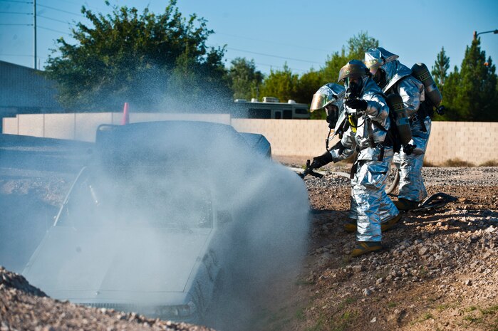Airmen from the 99th Civil Engineer Squadron Fire Department extinguish a simulated burning car Sept. 19, 2013, near the Mike O'Callaghan Federal Medical Center during a major aircraft crash response exercise at Nellis Air Force Base, Nev. The exercise tested Airmen, contractors and civilians in their response to a major aircraft incident. (U.S. Air Force photo/Senior Airman Brett Clashman)