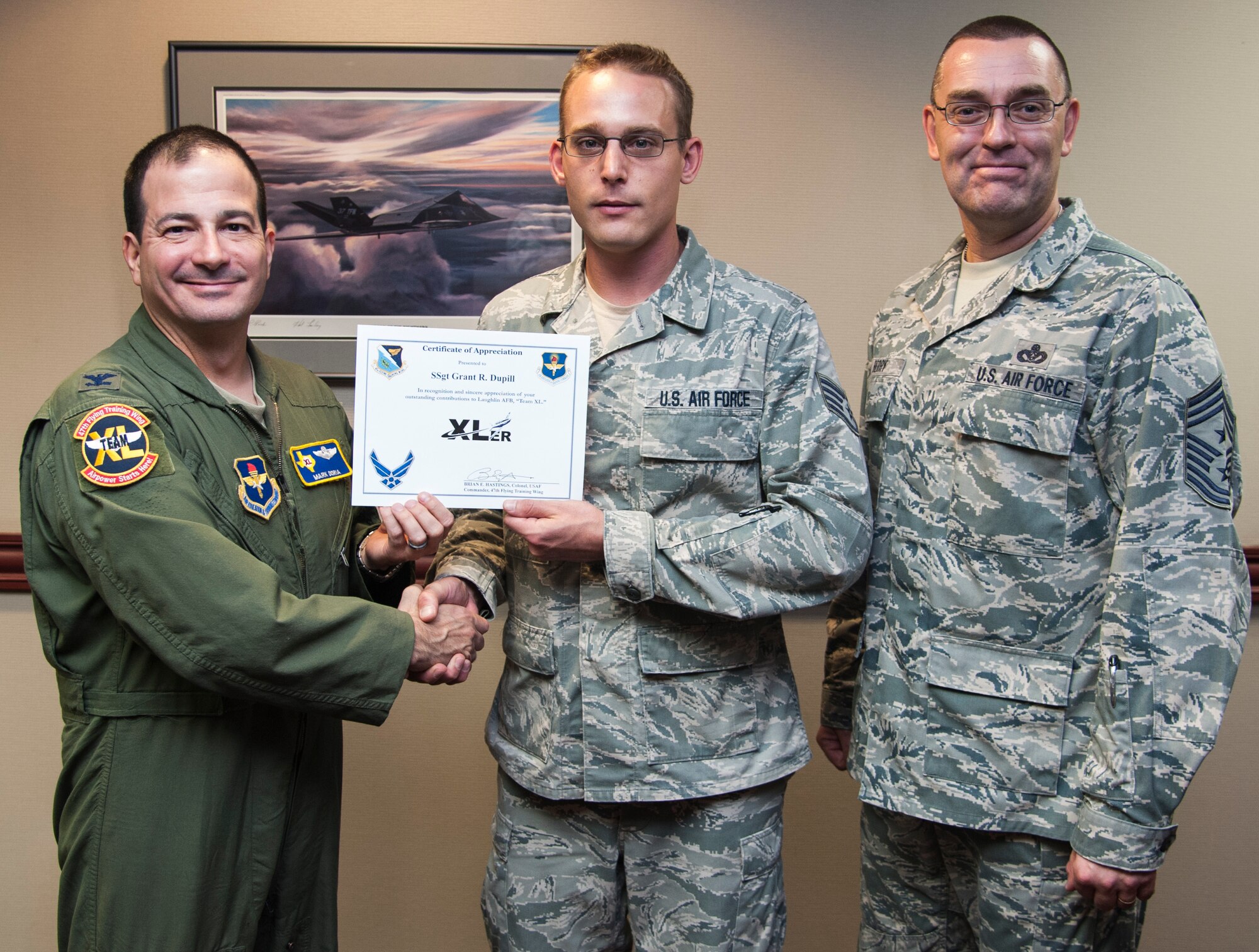 Staff Sgt. Grant Dupill, 47th Medical Operations Squadron Family Health shift supervisor, poses with Col. Mark Doria, 47th Flying Training Wing vice commander, and Chief Master Sgt. Garry Berry, 47th FTW command chief, after being presented the XLer of the week award here Sept. 19, 2013. The XLer is a weekly award chosen by wing leadership and given to those who consistently make outstanding contributions to Laughlin and their unit. (U.S. Air Force photo/Senior Airman John D. Partlow)