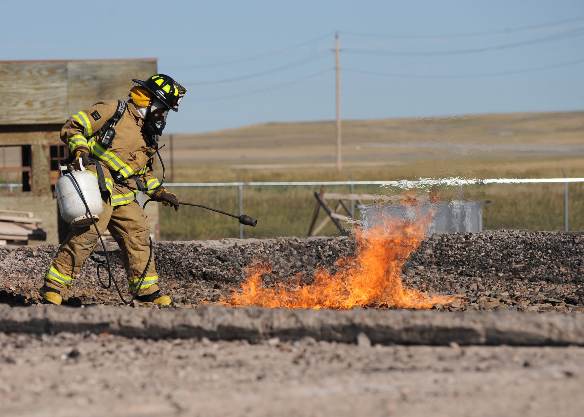 Jeremiah Hanna-Cruz, 28th Civil Engineer Squadron fire safety driver operator, ignites a fire in the base fire pit training area during a simulated aircraft fire training exercise at Ellsworth Air Force Base, S.D., Sept. 18, 2013. Ellsworth firefighters periodically conduct fire pit training in an effort to ensure all fire crews are prepared to respond to emergencies that occur during real world contingencies. (U.S. Air Force photo by Airman 1st Class Rebecca Imwalle / Released)