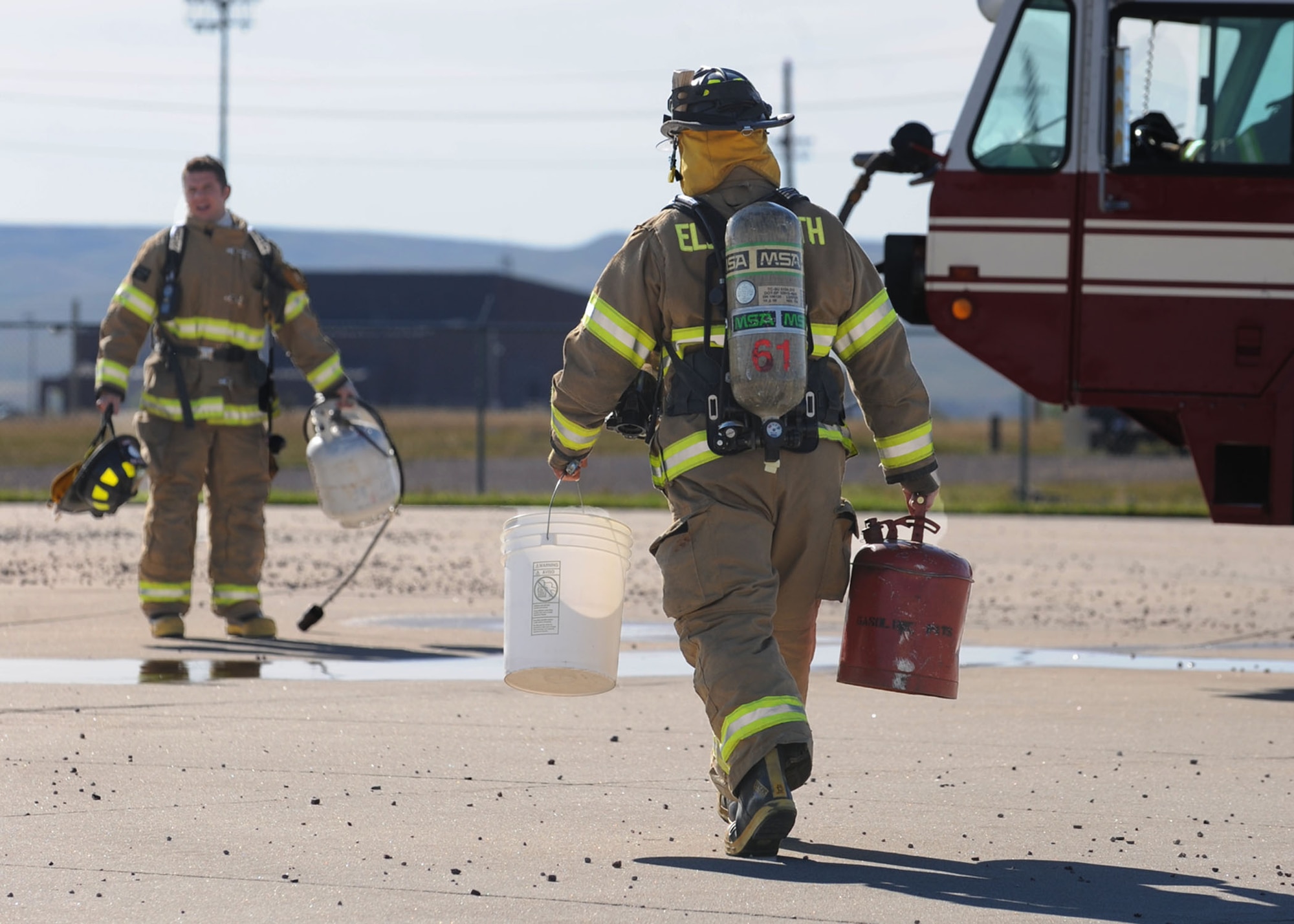 Jeremiah Hanna-Cruz (left), and Senior Airman Clinton Gatewood, 28th Civil Engineer Squadron fire safety driver operators, prepare to ignite a simulated aircraft fire during a pit burn training exercise at Ellsworth Air Force Base, S.D., Sept. 18, 2013. Fire pit training is designed to prepare firefighters to safely and effectively respond to aircraft fires. (U.S. Air Force photo by Airman 1st Class Rebecca Imwalle / Released)