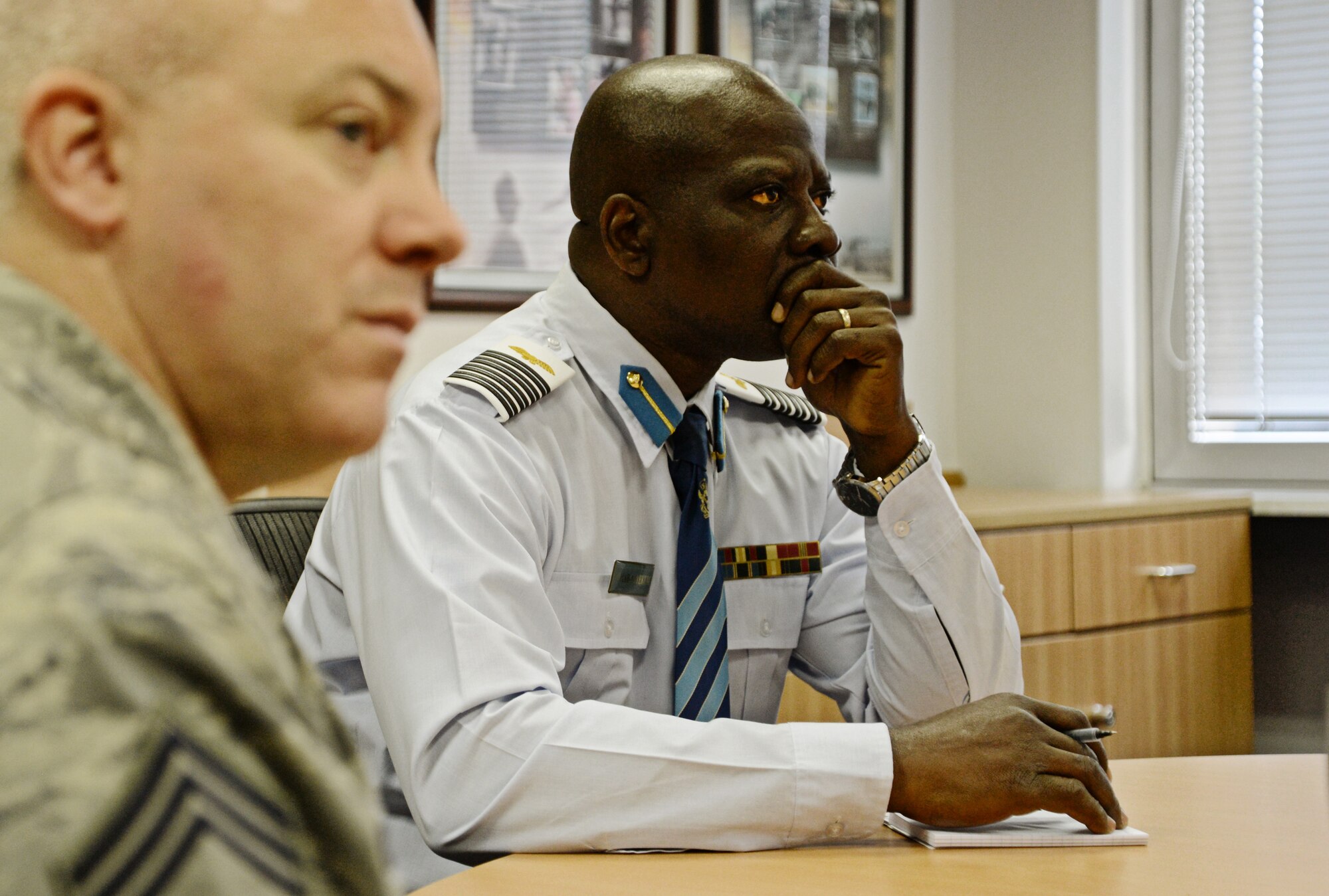 Col. Appiah-Agyekum of the Ghana air force and Chief Master Sgt. Chris Moore, Kisling NCO Academy commandant, listen in on a briefing about the academy on Kapaun Air Station, Germany Sept. 25, 2013. Leaders of Ghana's air force visited the NCO academy to better understand how the U.S. Air Force develops its enlisted force. They plan on taking the information back to develop their own professional military education program in Ghana. (U.S. Air Force photo/ Staff Sgt. Ryan Crane)