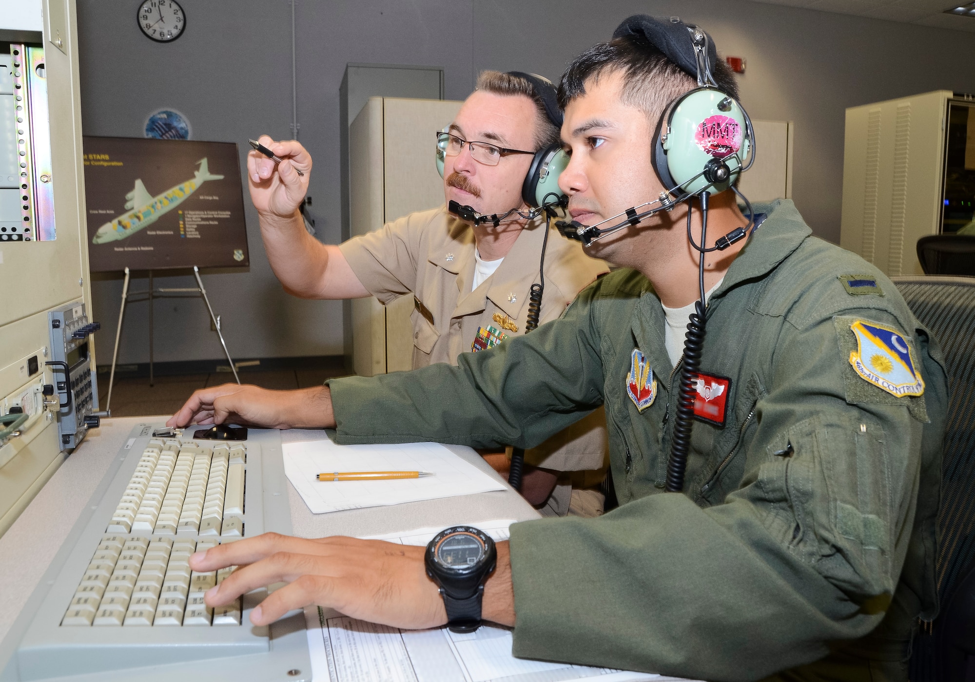 U.S. Air Force 1st Lt. Toby, 16th Airborne Command and Control Squadron air weapons officer, works alongside Cmdr. Mike Reed, U.S. Navy Third Fleet liaison officer, from a simulated E-8C Joint STARS operator workstation during Coalition Virtual Flag 13-4, Robins Air Force Base, Ga., Sept. 18, 2013. Exercise planners and aviators from the 116th and 461st Air Control wings, participated in the virtual exercise along with units from 23 different locations worldwide including Australia, Canada and the United Kingdom. Reed spent the week with JSTARS operators to learn more about how the Navy can benefit from the command and control, intelligence, surveillance and reconnaissance capabilities of the Joint STARS platform. (U.S. Air National Guard photo by Master Sgt. Roger Parsons/Released) (Portions of the photo have been blurred and the full name of the aviator has been withheld for security purposes)