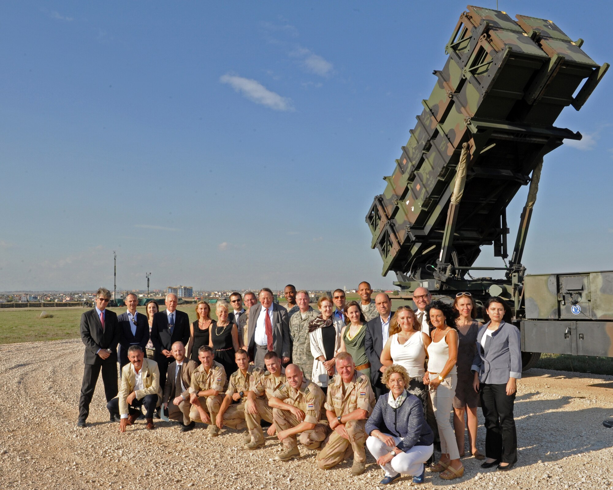 Members of the NATO Parliamentary Assembly, 1st Netherlands Ballistic Missile Defense Task Force soldiers and 39th Air Base Wing Airmen pose for a photo in front of the cityscape of Adana, Turkey and an MIM-104 Patriot Sept. 24, 2013 at Incirlik Air Base, Turkey. The tour included a look at the missile defense systems protecting Adana and part of the southern border of the NATO Alliance. (U.S. Air Force photo by Senior Airman Chase Hedrick/Released)