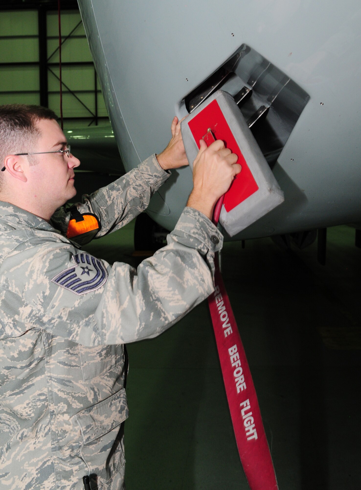 U.S. Air Force Tech. Sgt. Adam Smith, 95th Reconnaissance Squadron instrument and flight controls craftsman from Stratford, Okla., removes a protective cover from the body of an RC-135 Rivet Joint Sept. 11, 2013, during maintenance of an RC-135 Rivet Joint in Hangar 814 on RAF Mildenhall, England. As the lead flightline expediter, Smith manages Airmen in multiple career fields, as well as all of the maintenance on the RC-135s. Regular maintenance on the aircraft is vital. Smith and his team take care of all instruments and flight controls used by the pilots, ensuring everything works correctly. (U.S. Air Force photo by Karen Abeyasekere/Released)