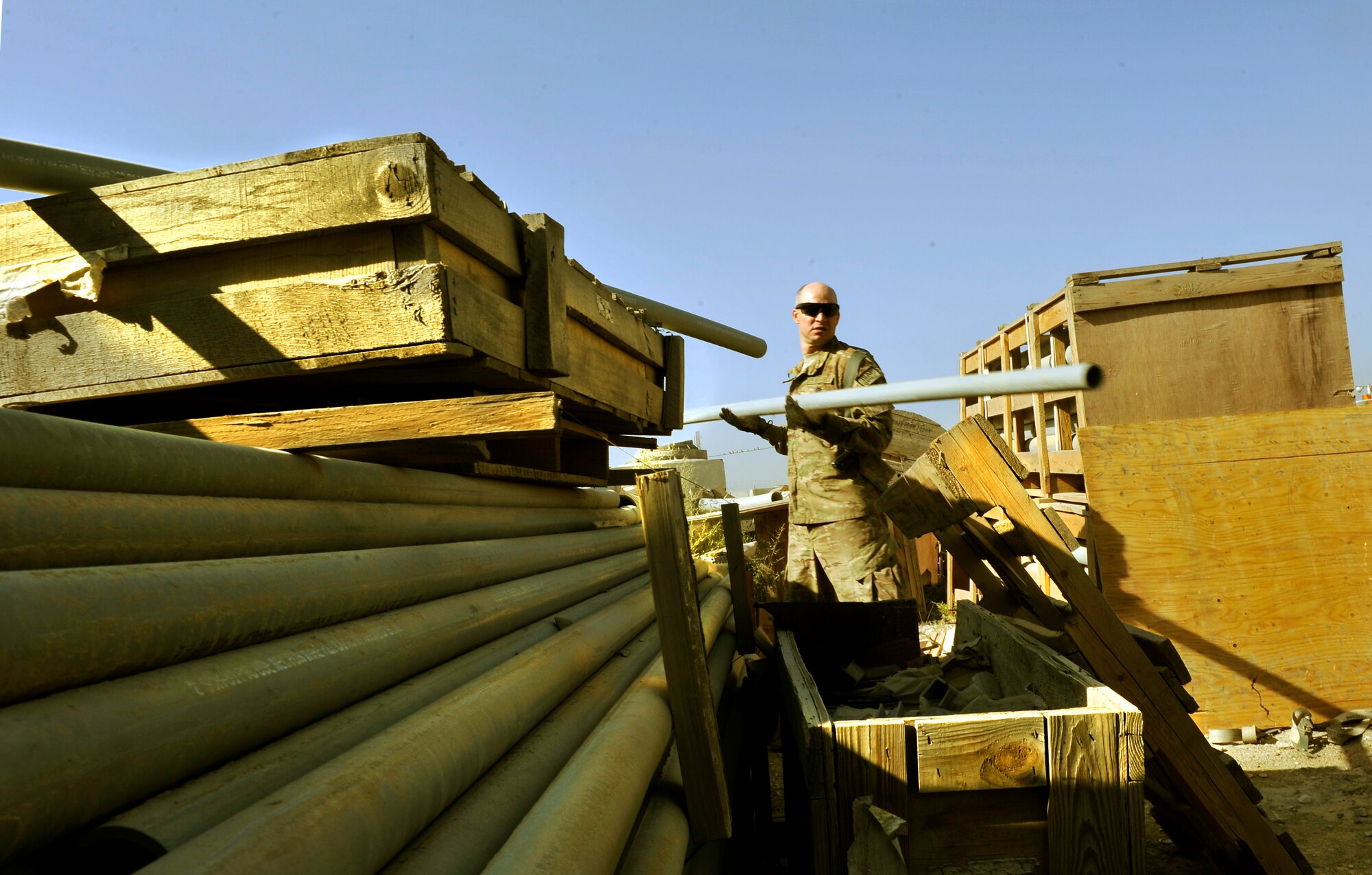 Master Sgt. Douglas Threatt, 455th Expeditionary Communications Squadron Cyber Maintenance Section Chief, picks up equipment and conduit from the storage yard on Bagram Airfield, Afghanistan. The equipment will be used to build a communications equipment room and install fiber optic cables. Threatt is deployed from Ramstein Air Base, Germany. (U.S. Air Force photo/ Staff Sgt. Stephenie Wade)