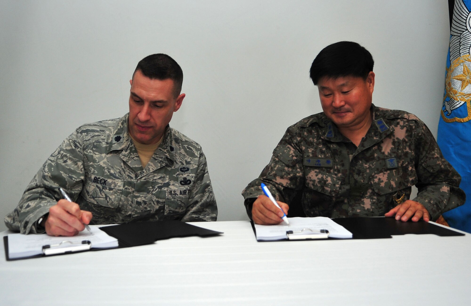Lt. Col. Jason Beck, 51st Security Forces Squadron commander, and Republic of Korea air force Lt. Col. Gyu Hwan Lee, Military Police Squadron commander, sign copies of the Air Force and ROKAF Agreement for Base Security and Law Enforcement at Osan Air Base, ROK, Sept. 24, 2013. The agreement covers several aspects of security for Osan’s joint environment, including the necessity for ROKAF Airmen to use the Defense Biometric Identification System. (U.S. Air Force photo/Airman 1st Class Ashley J. Thum)