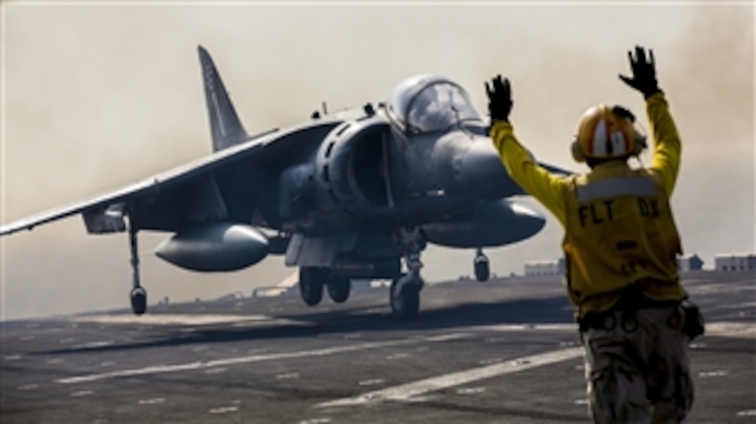 A flight deck crewman directs the pilot of a U.S. Marine Corp AV-8B Harrier as it touches down on the flight deck of the USS Kearsarge (LHD 3) during flight operations at sea on Sept. 24, 2013.  The Harrier is assigned to Marine Medium Tiltrotor Squadron 266 (Reinforced) and is embarked on board the Kearsarge as part of the 26th Marine Expeditionary Unit.  