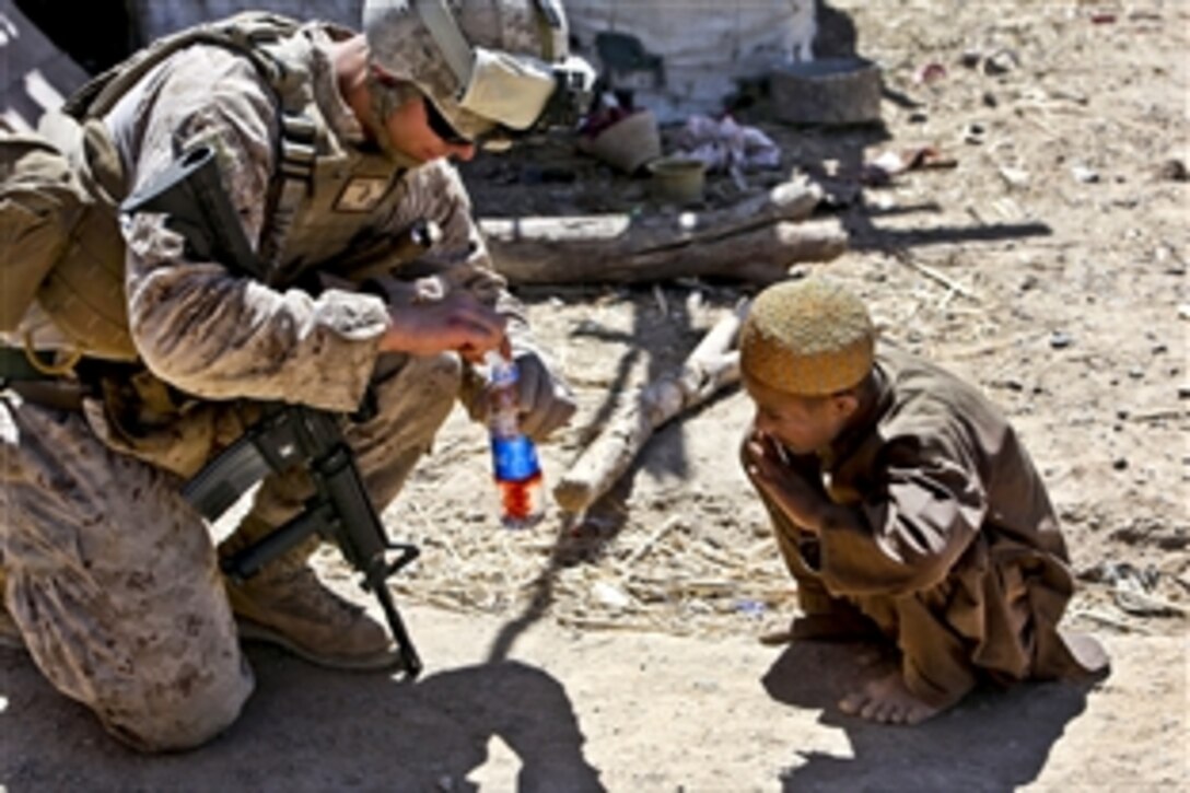 A U.S. Marine mixes a fruit drink for an Afghan boy while on patrol in Barrmo in the Washir district, Afghanistan, Sept. 19, 2013.