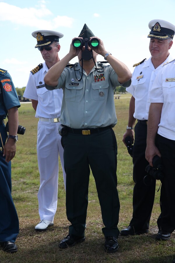 Colonel Armando J. Alaniz, from the Army of Nicaragua, looks through binoculars in order to a platoon fire and maneuver attack conducted by 1st Battalion, 8th Marine Regiment, 2nd Marine Division, at Range G-6 aboard Marine Corps Base Camp Lejeune. A total of 18 countries were a part of the 2013 fall tour for naval attachés from Sept. 23 through 24. A colonel in the Army of Nicaragua is the equivalent of a Colonel in the Marine Corps.